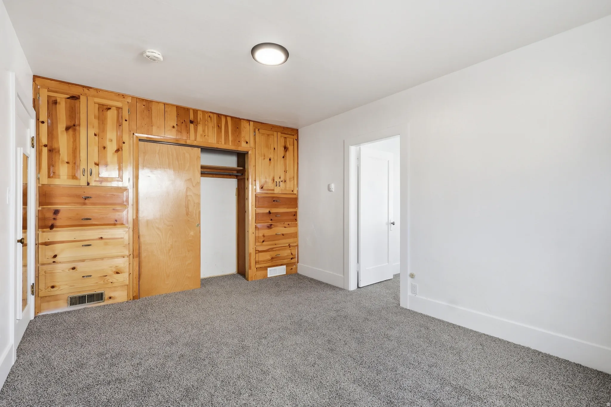 Unfurnished bedroom featuring carpet floors, a closet, and wooden walls