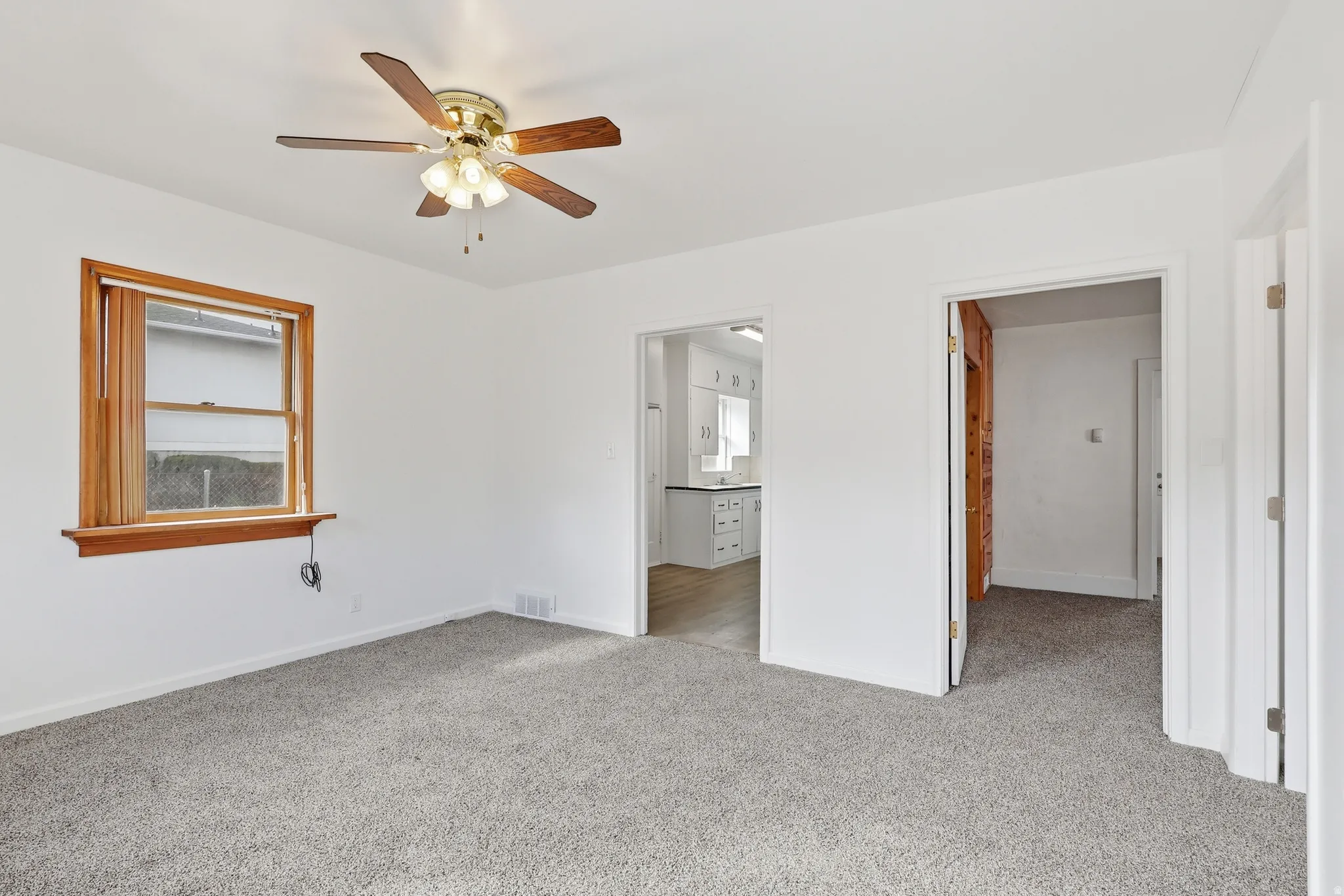 Unfurnished bedroom with connected bathroom, light colored carpet, and ceiling fan