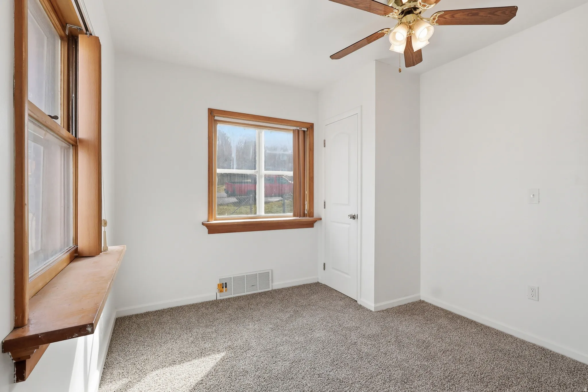 Carpeted empty room with baseboards and a ceiling fan