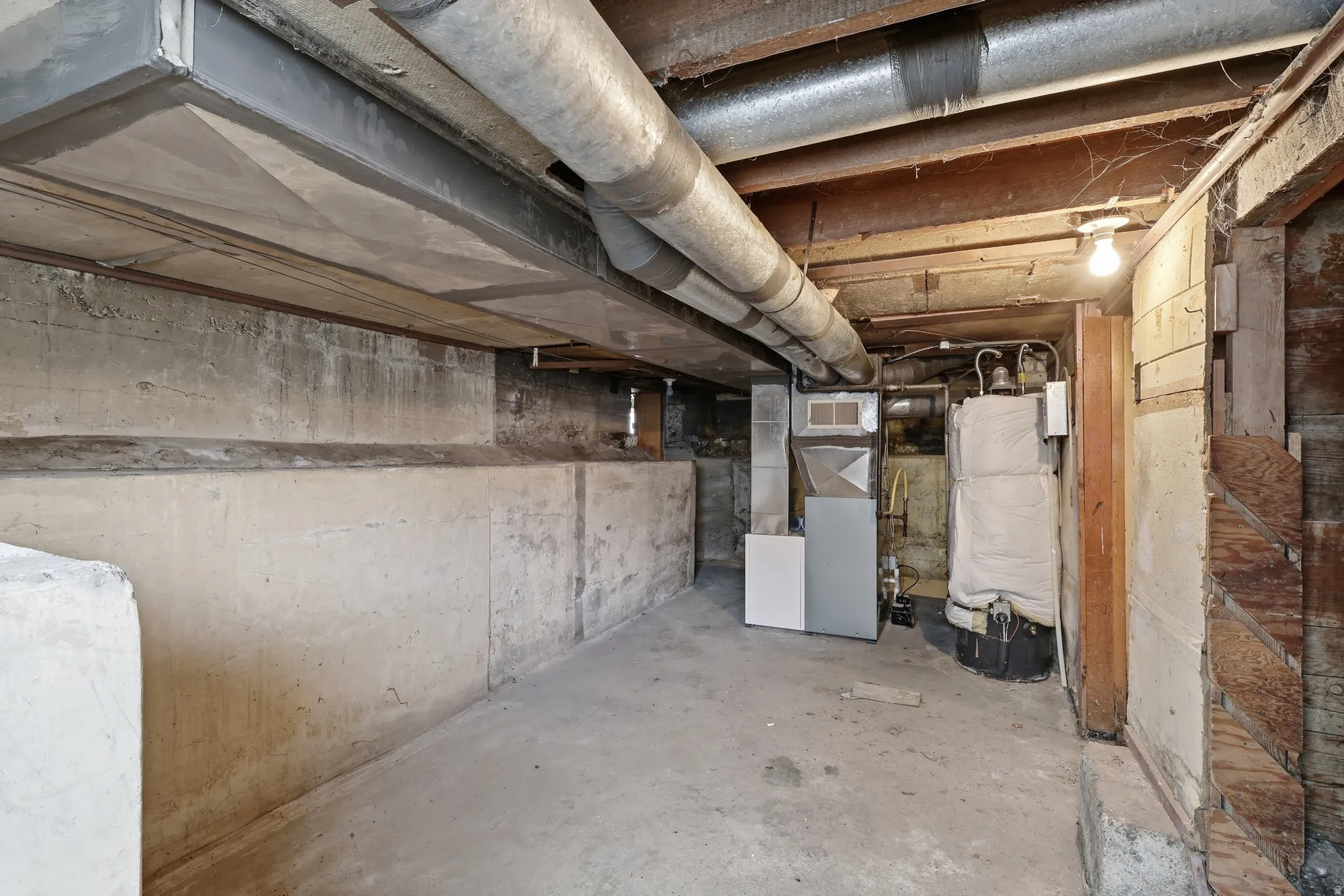 Unfinished basement with heating unit and water heater