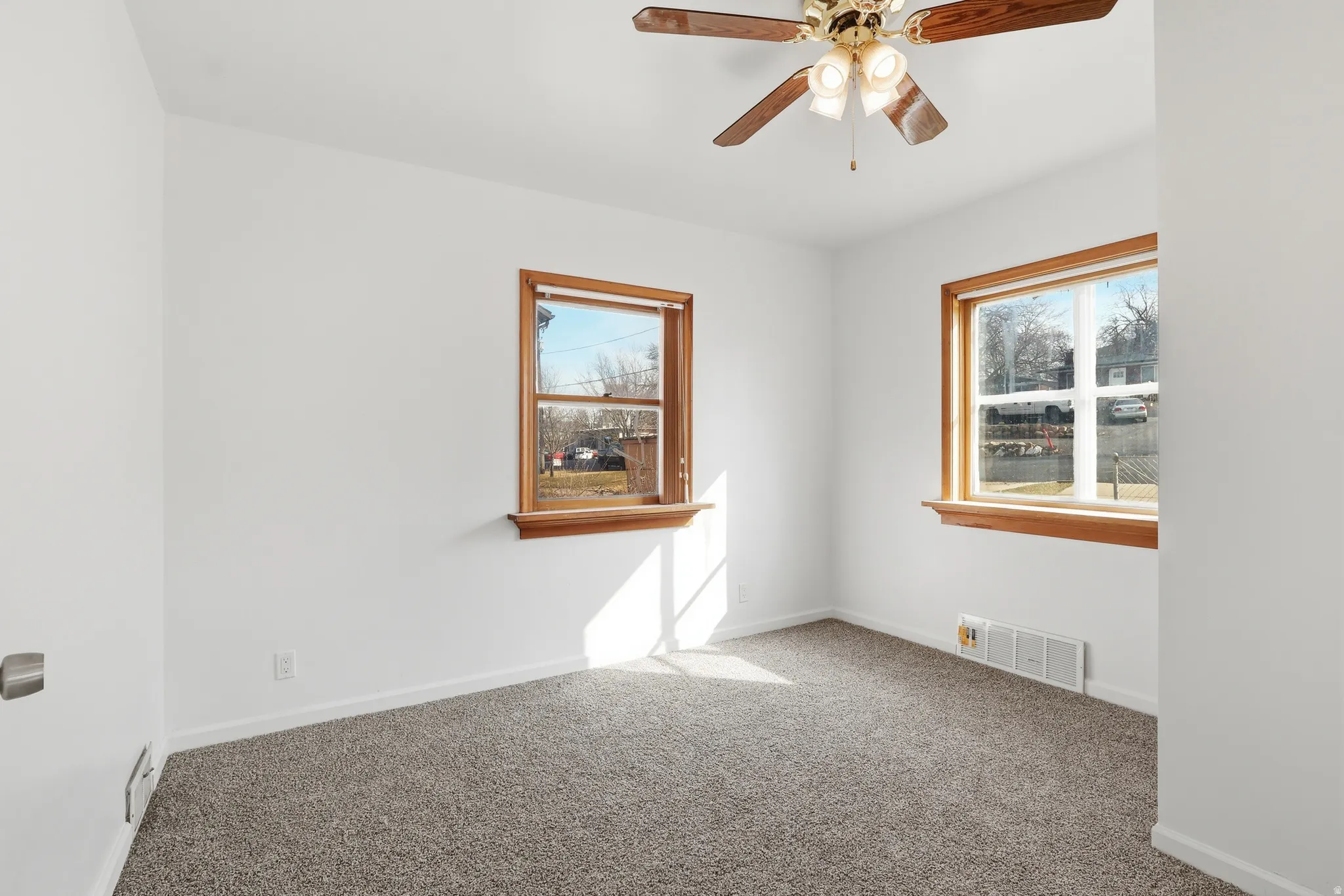 Carpeted empty room featuring ceiling fan and baseboards