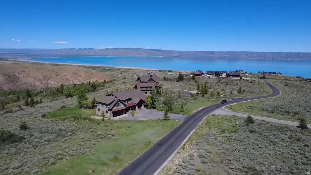 Property featuring a multi-level structure with stone and wood siding, a paved driveway, and an attached garage