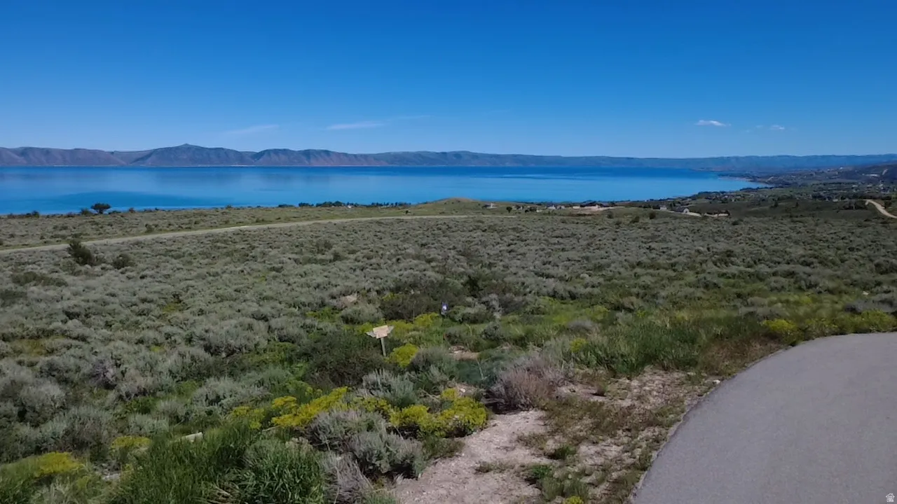 Expansive land parcel featuring natural shrubbery and distant water frontage