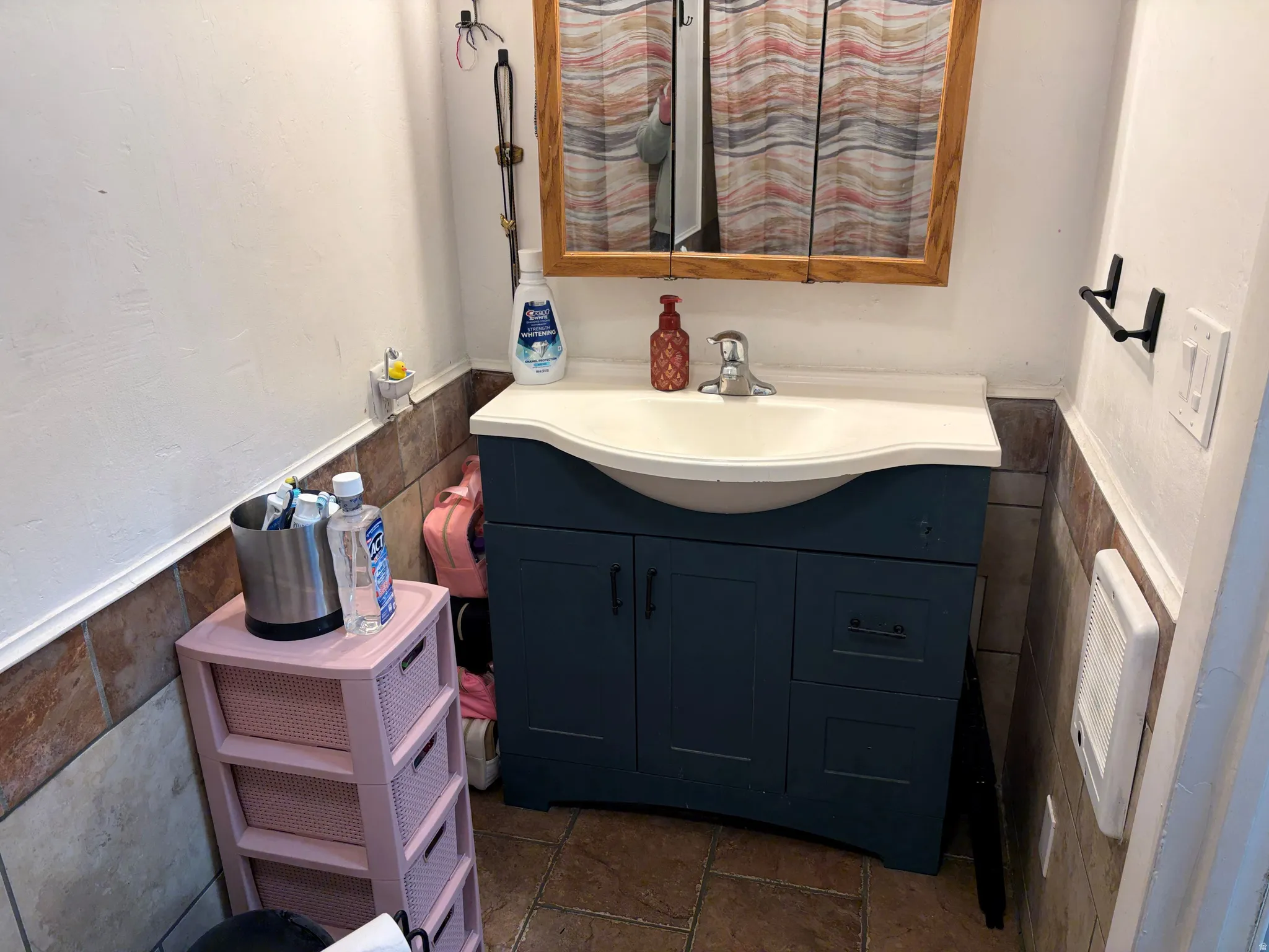 Bathroom with wainscoting, tile walls, and vanity