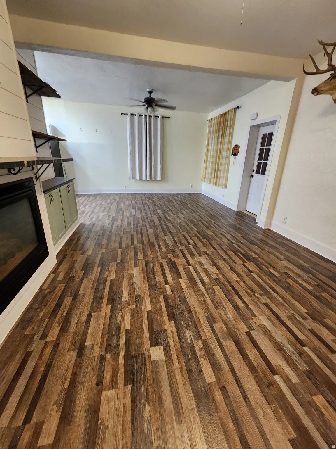 Unfurnished living room with dark wood finished floors, a ceiling fan, and a large fireplace