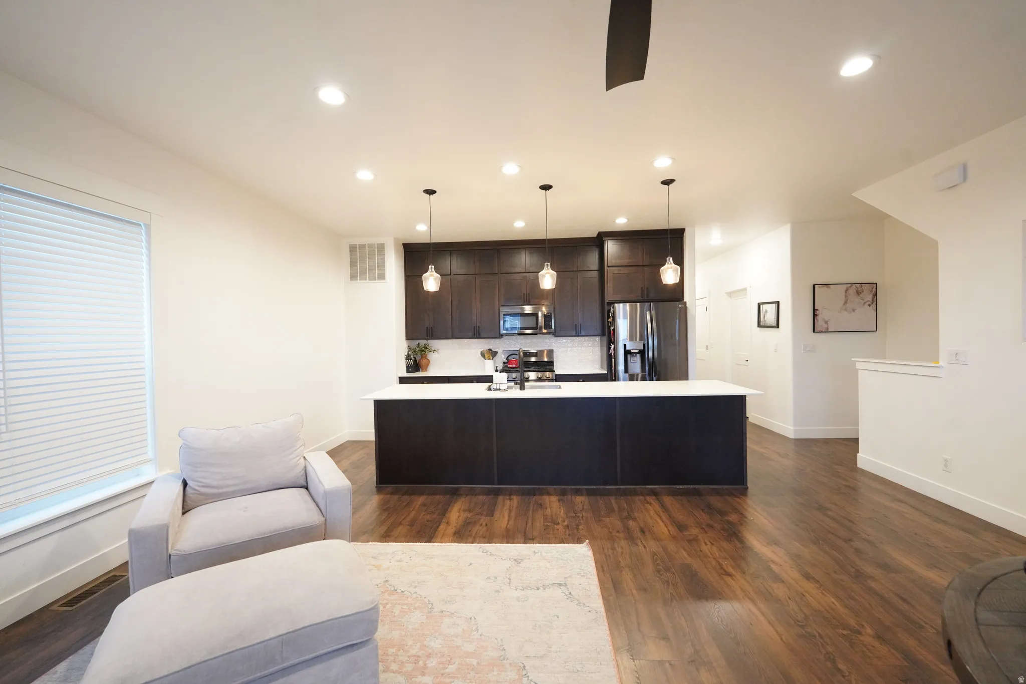 Kitchen featuring a large island, stainless steel appliances, dark wood finish cabinets, and dark wood finished floors