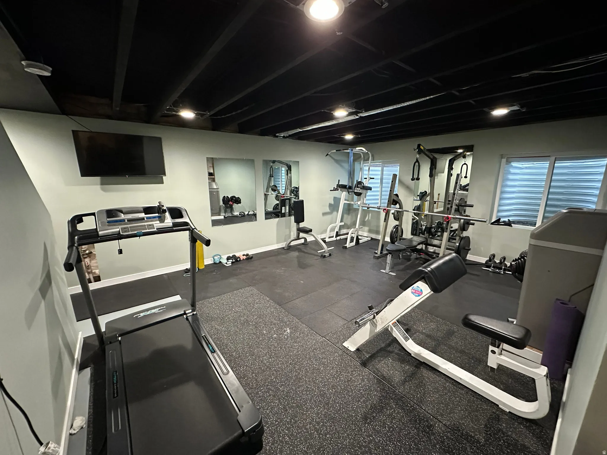 Workout area in basement featuring dark rubber flooring