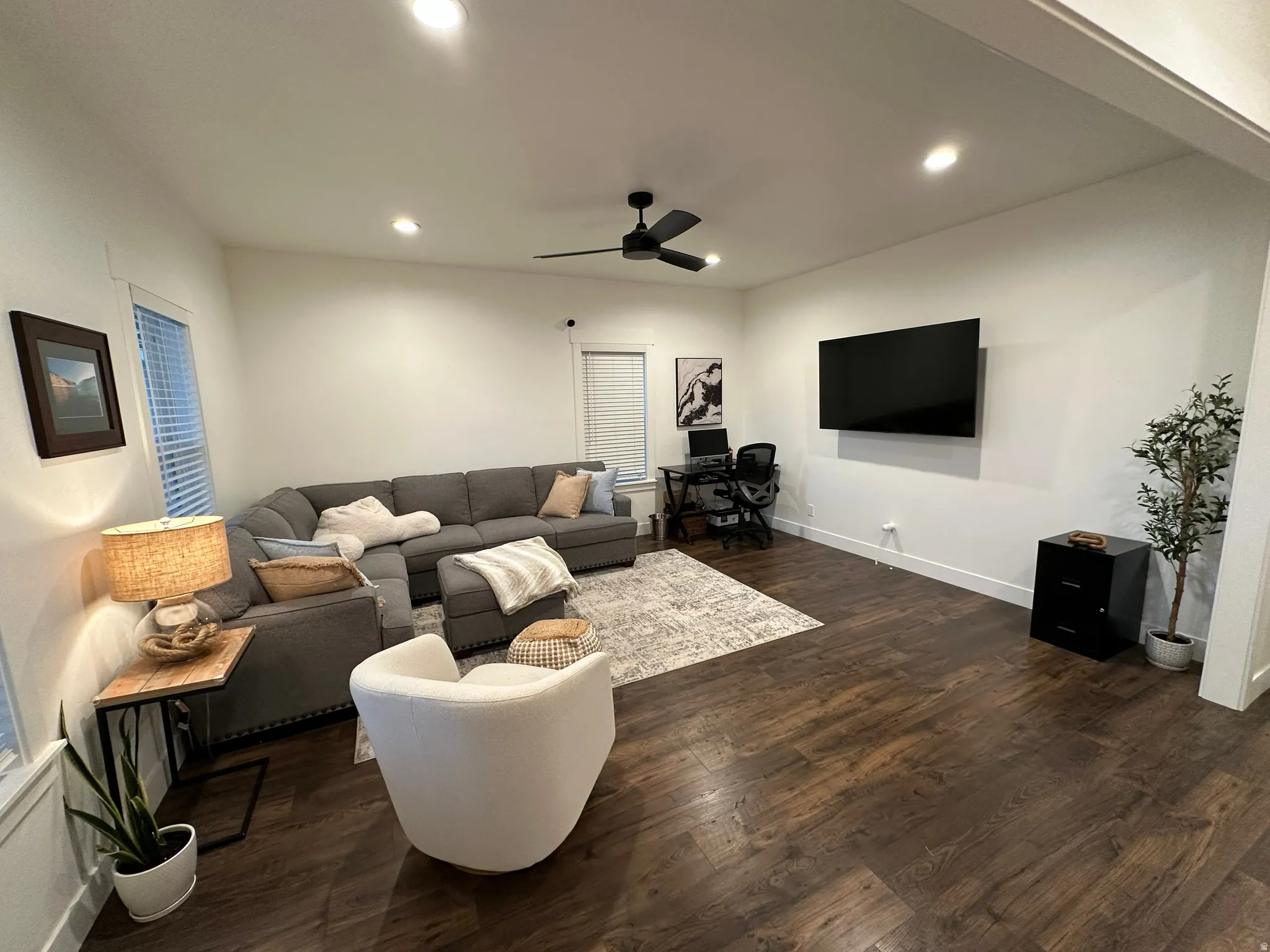 Living room with dark wood-style floors, recessed lighting, ceiling fan