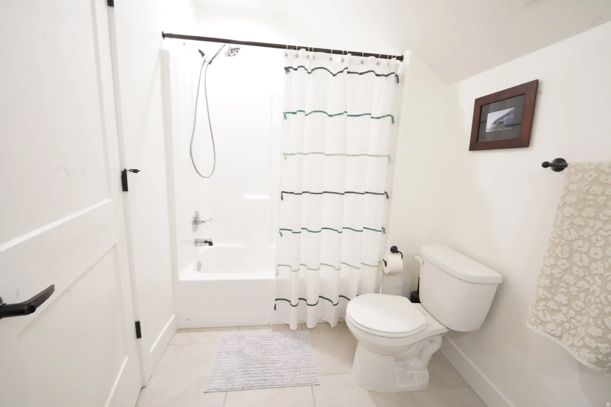 Bathroom with shower / tub combo with curtain and light tile patterned flooring