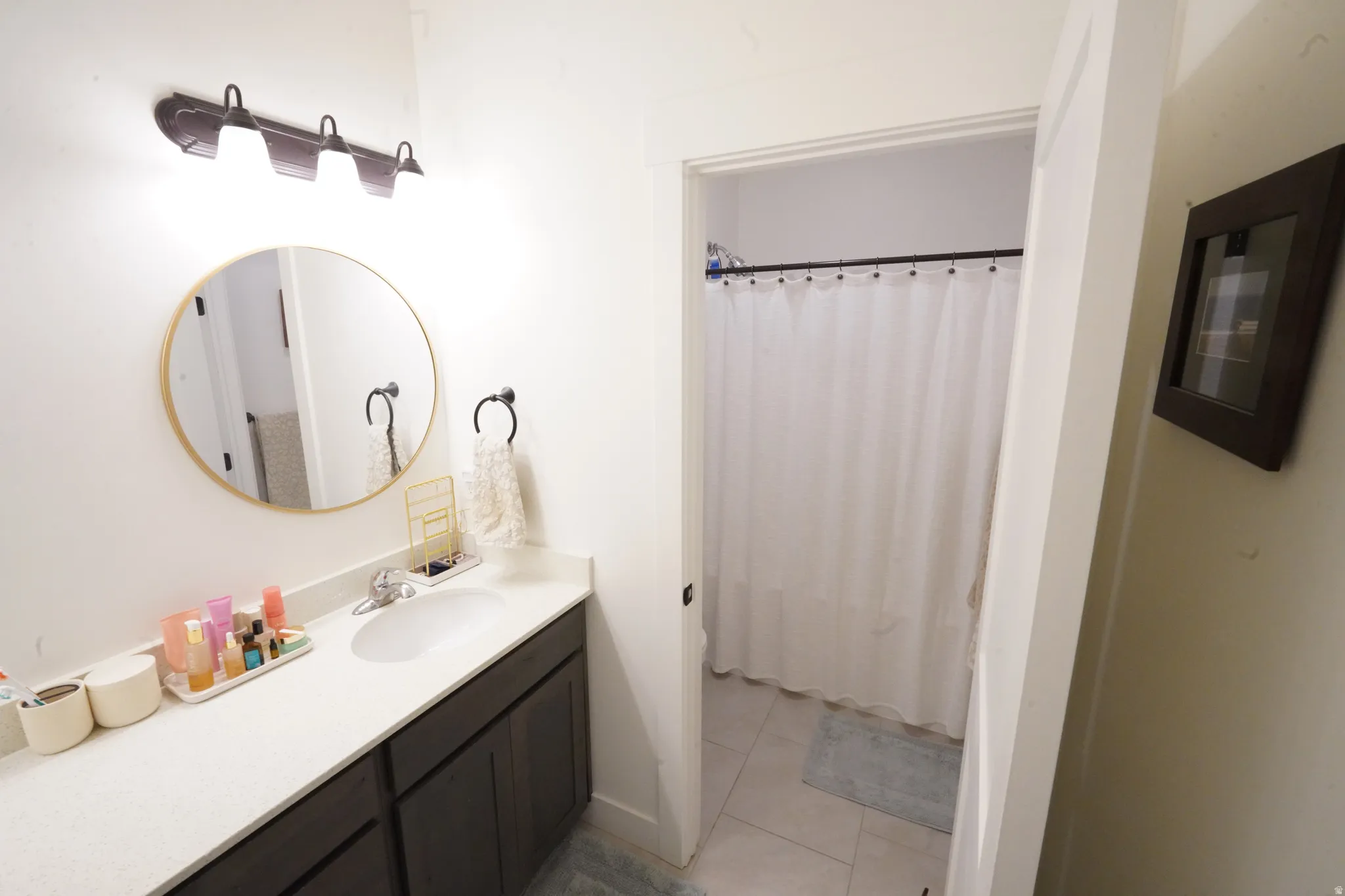 Bathroom with vanity, a shower with shower curtain, and light tile patterned floors