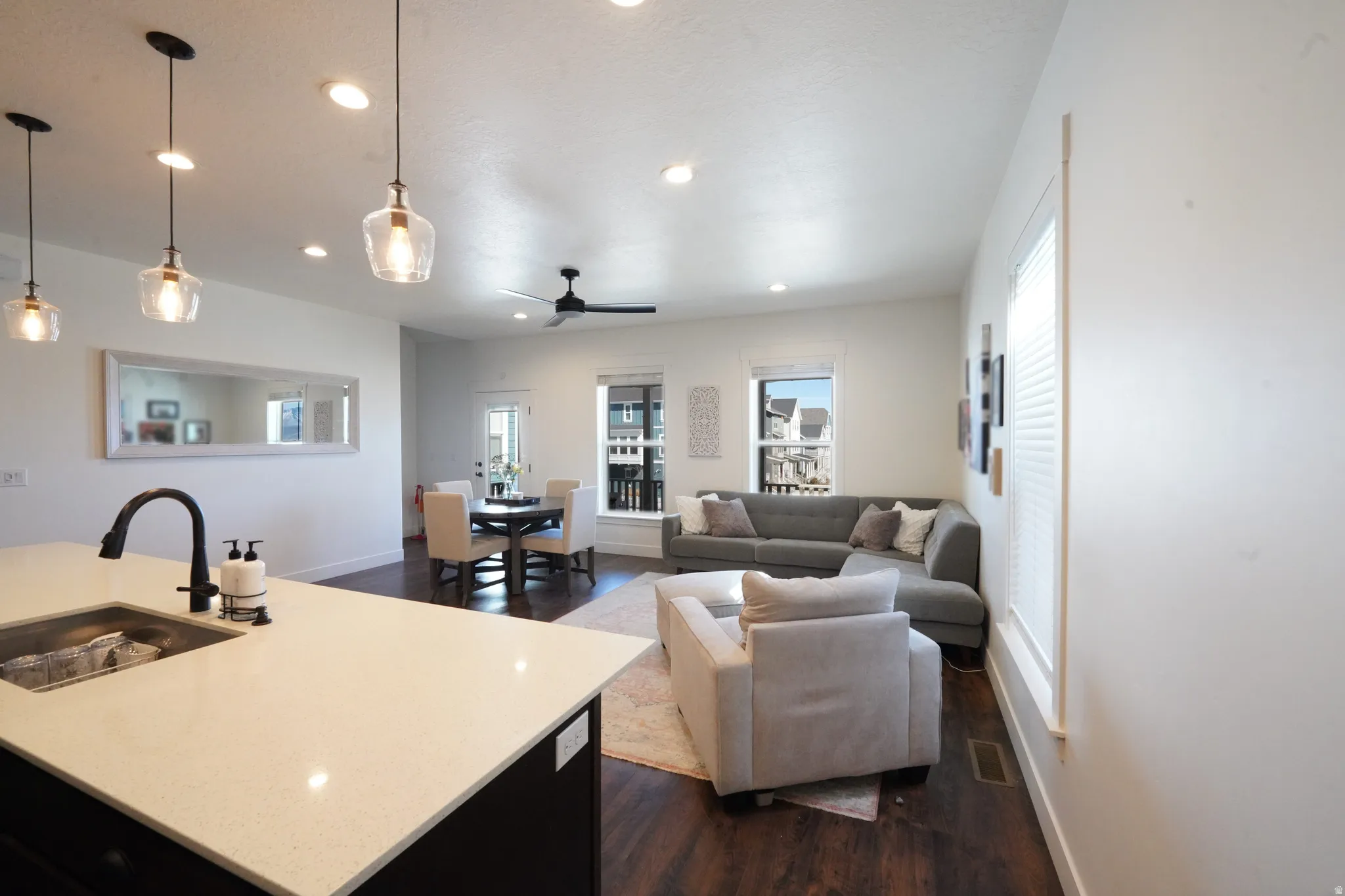 Living room with dark wood finished floors, recessed lighting, ceiling fan, and plenty of natural light