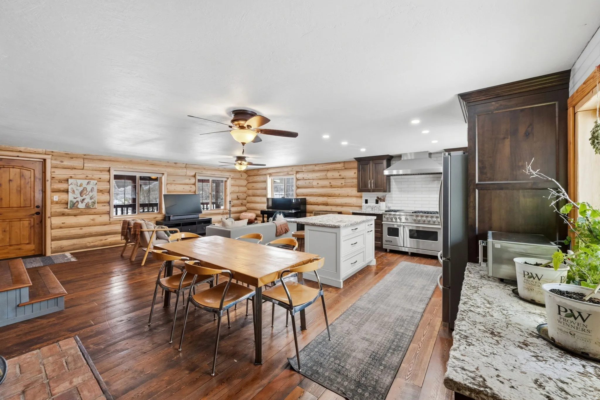 Dining room featuring dark wood-type flooring, log walls, ceiling fan, and recessed lighting