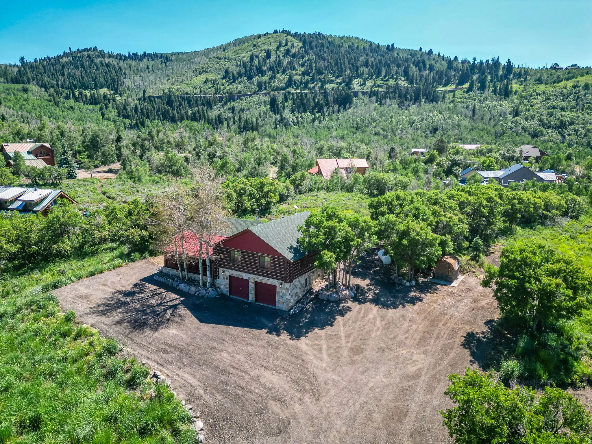 Log cabin style property featuring a red metal roof and stone foundation