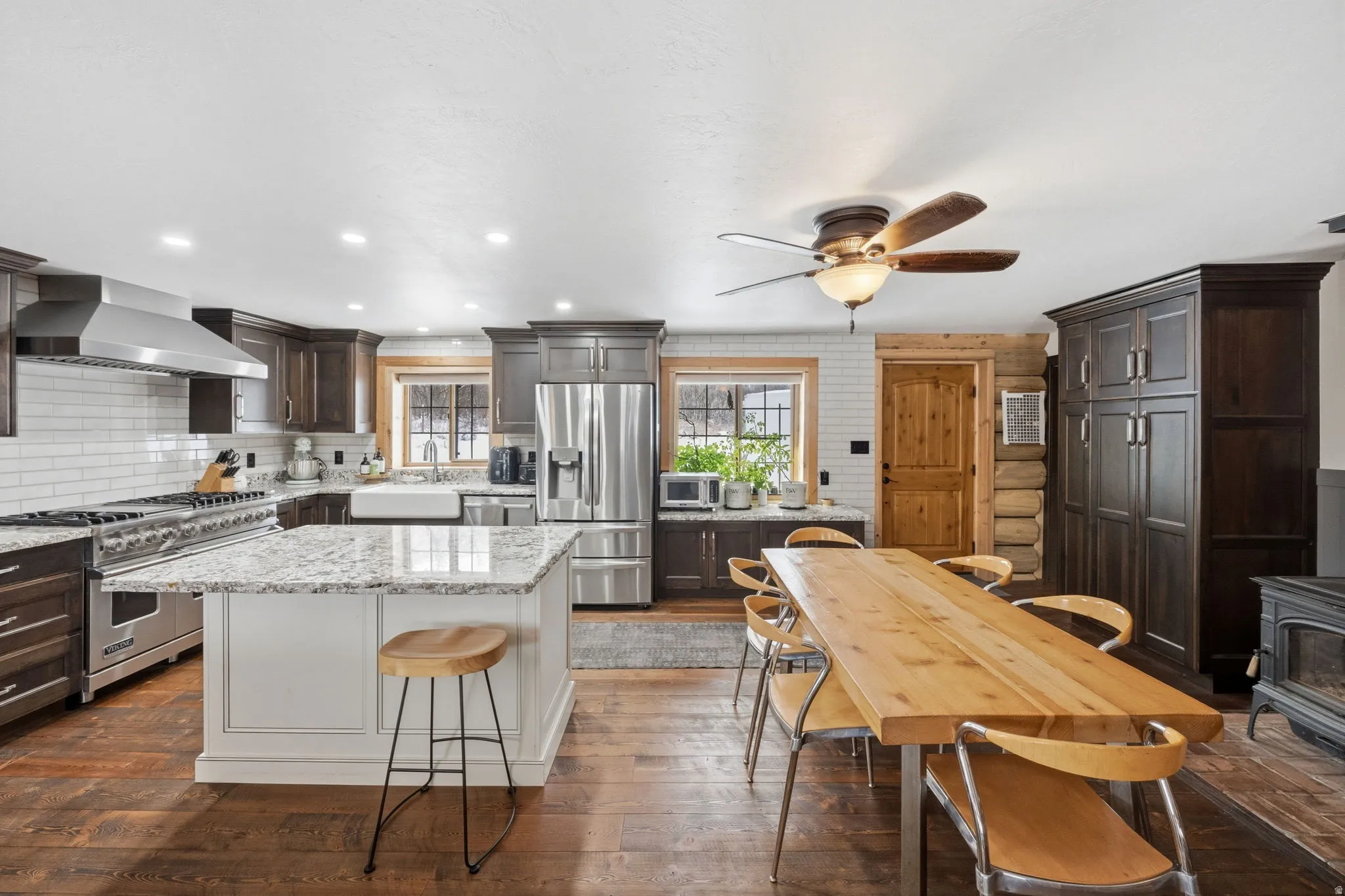 Two tone kitchen with light stone counters, stainless steel appliances, dual tone cabinets, dark wood-style floors, and a kitchen island