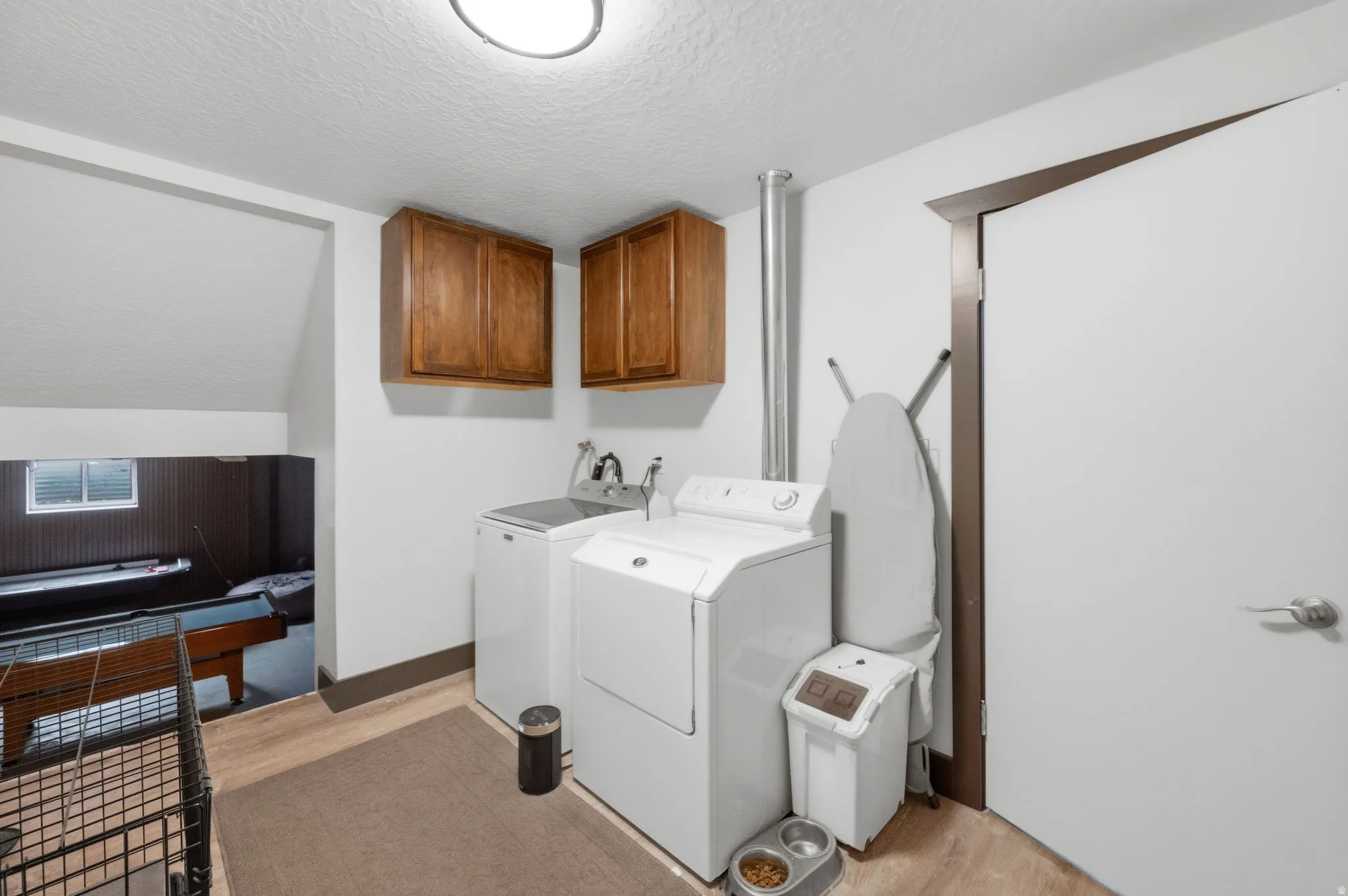 Laundry room featuring cabinet space, a textured ceiling, light wood-style flooring, and separate washer and dryer