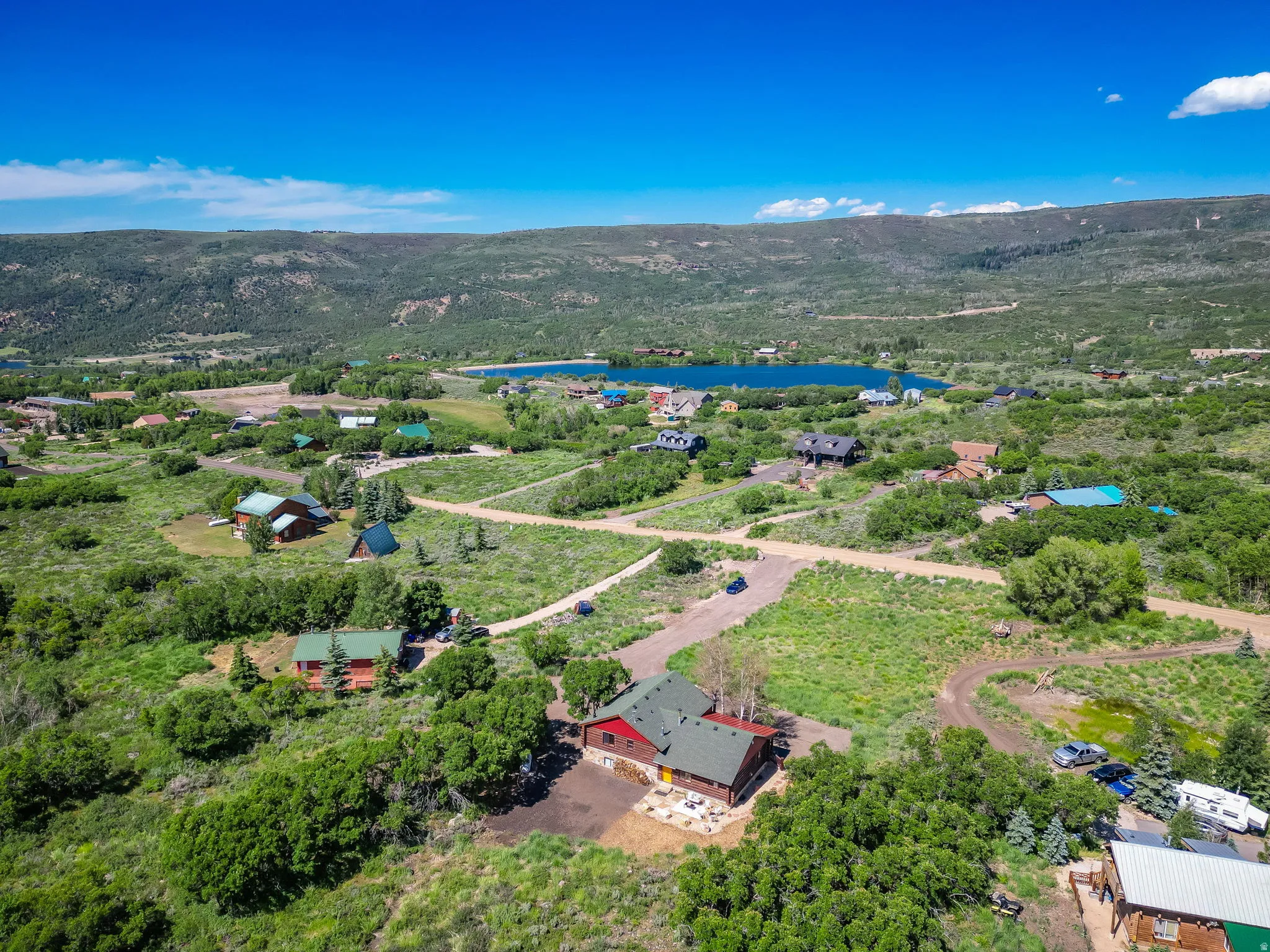 Aerial perspective showcasing a property with a red exterior and green roof surrounded by natural landscaping