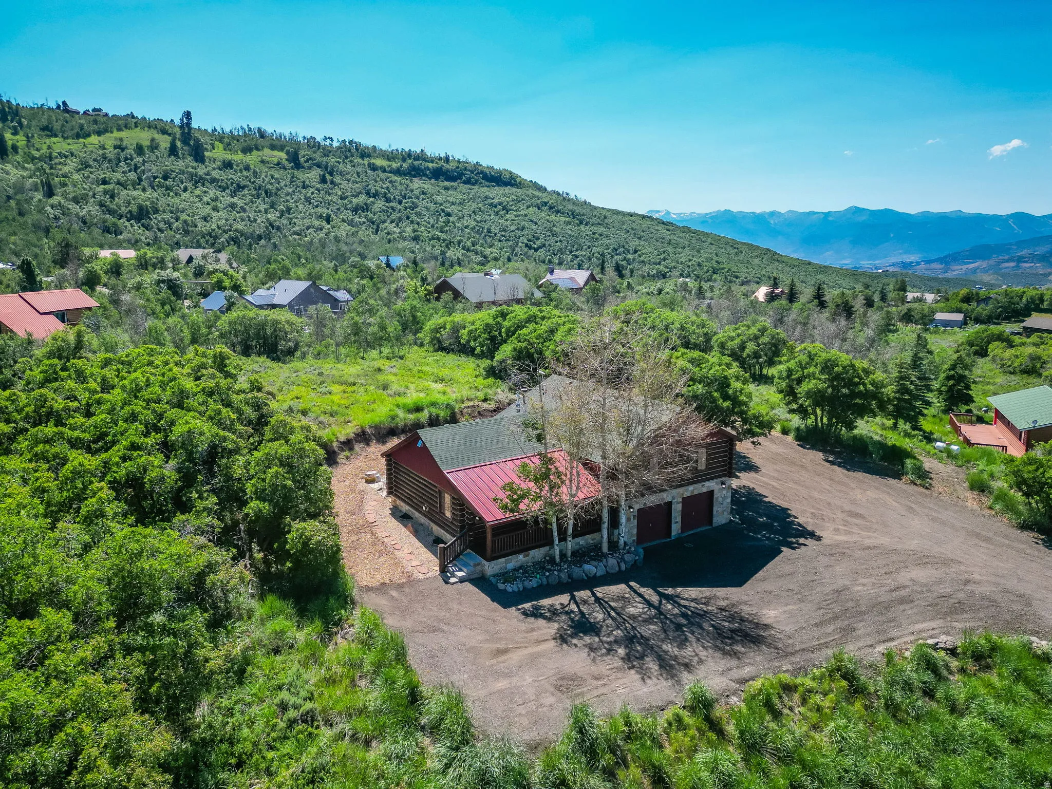 Log-style residence with a red-hued roof, two-car garage, and a gravel driveway