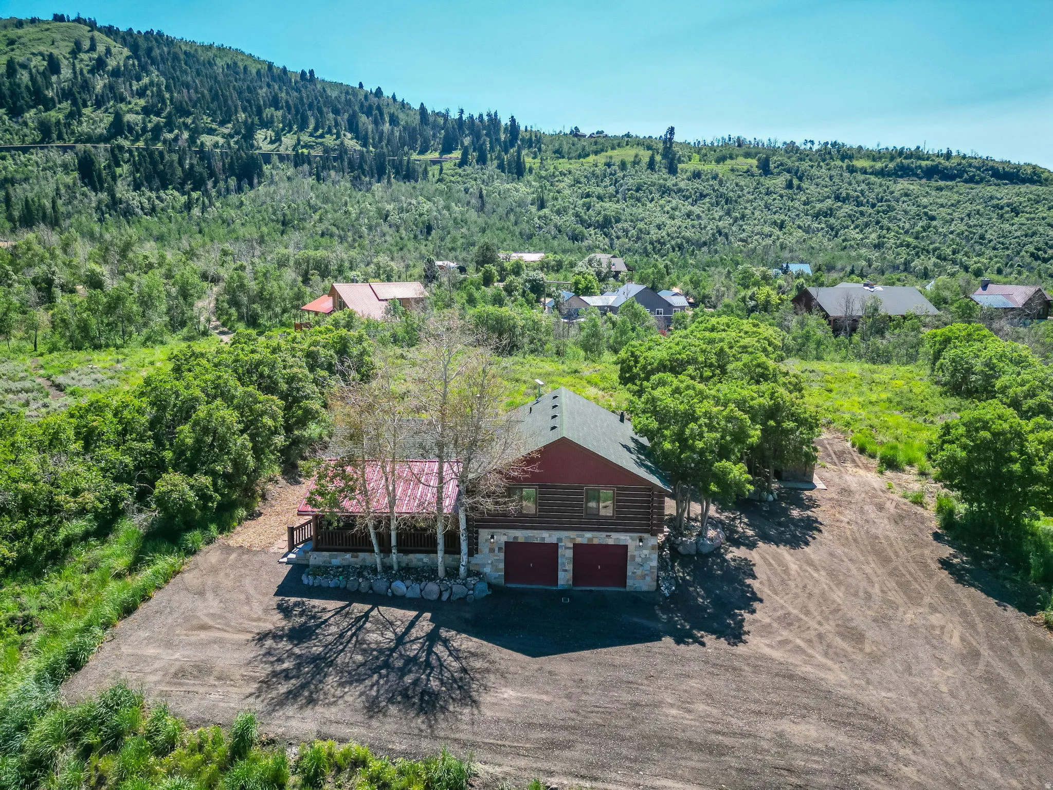 Log cabin style exterior with a red metal roof and stone foundation