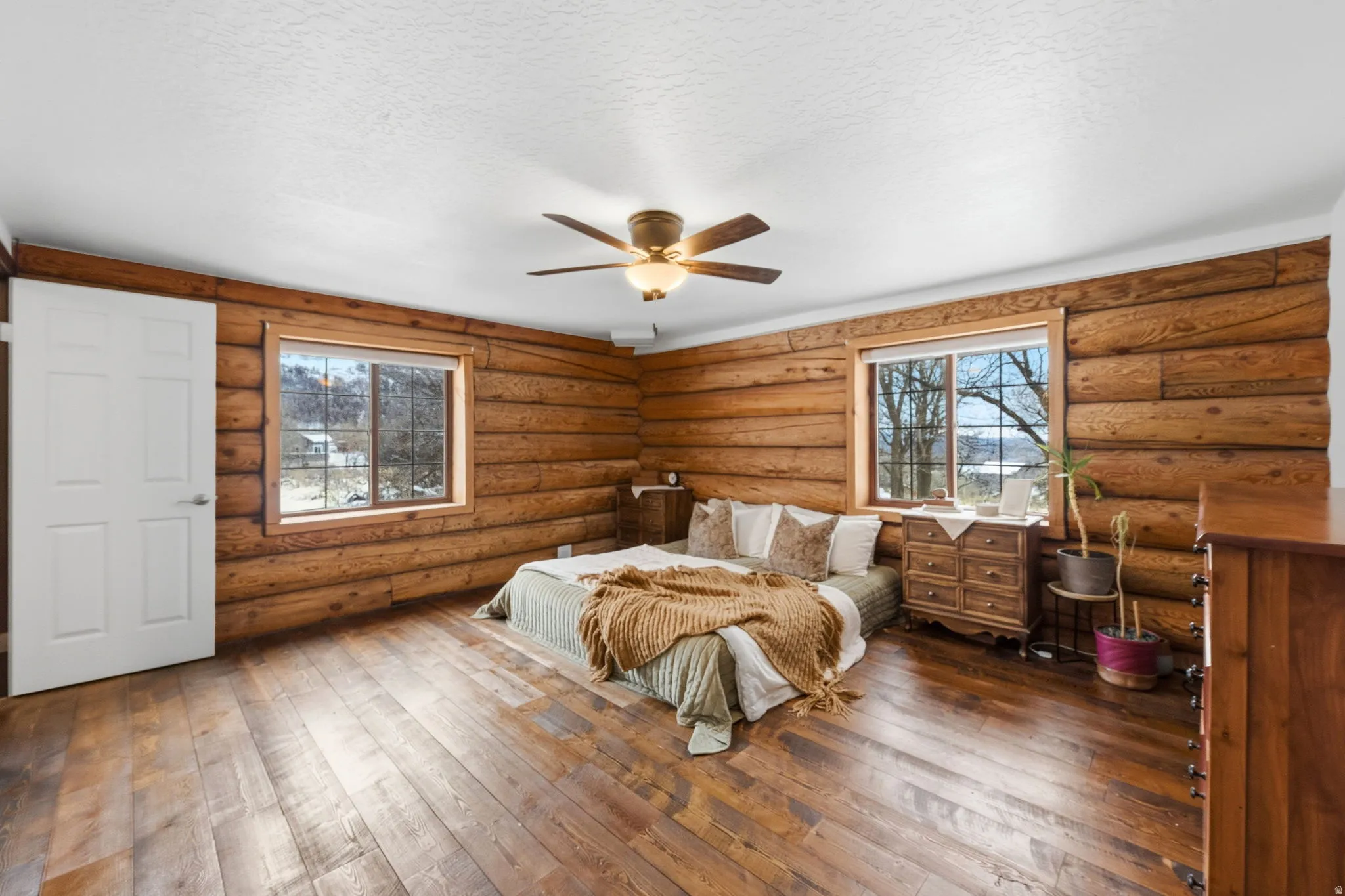 Bedroom featuring rustic walls, dark wood-style floors, ceiling fan, and a textured ceiling