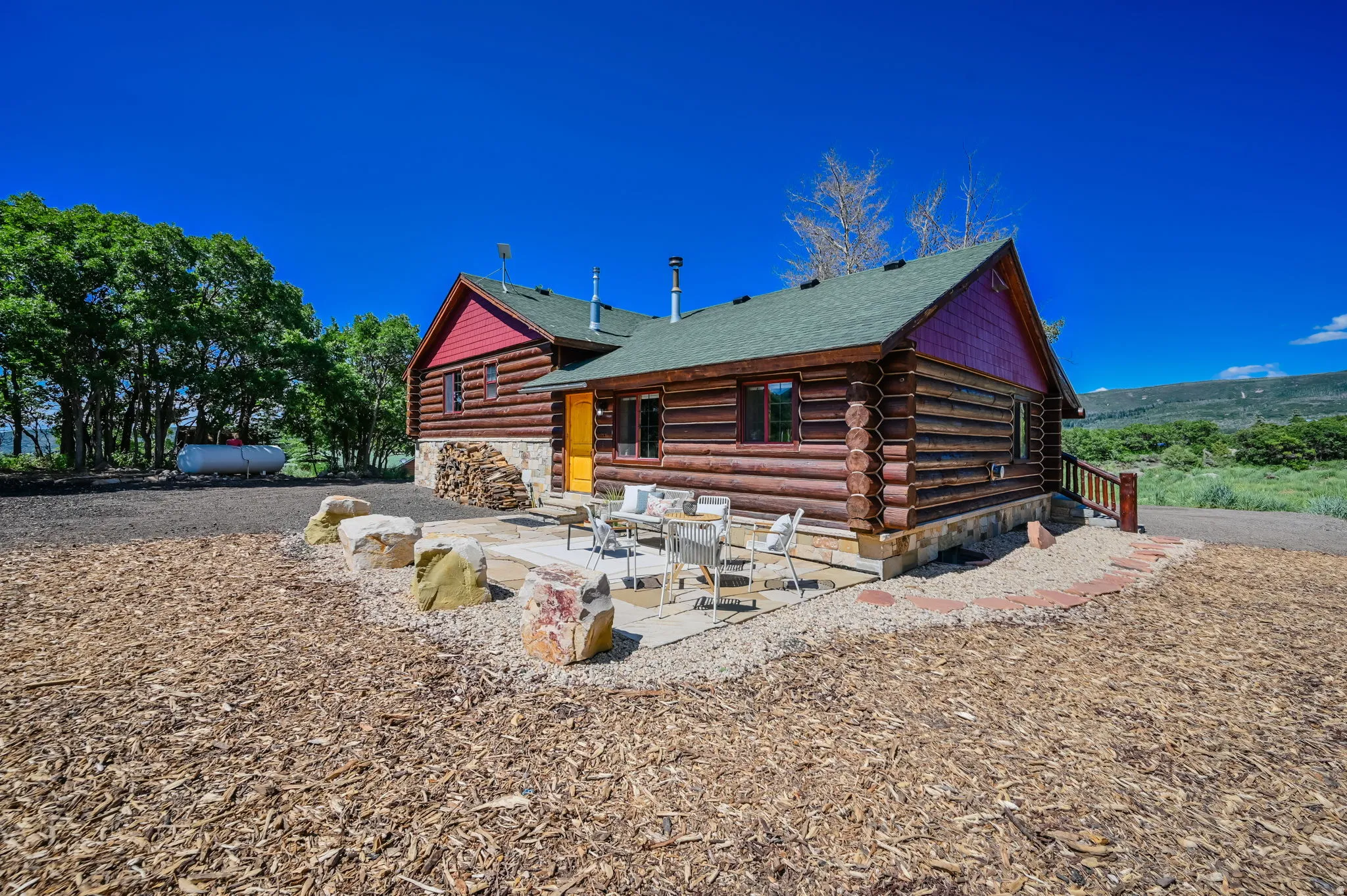 Log cabin exterior with a green shingled roof and red gables
