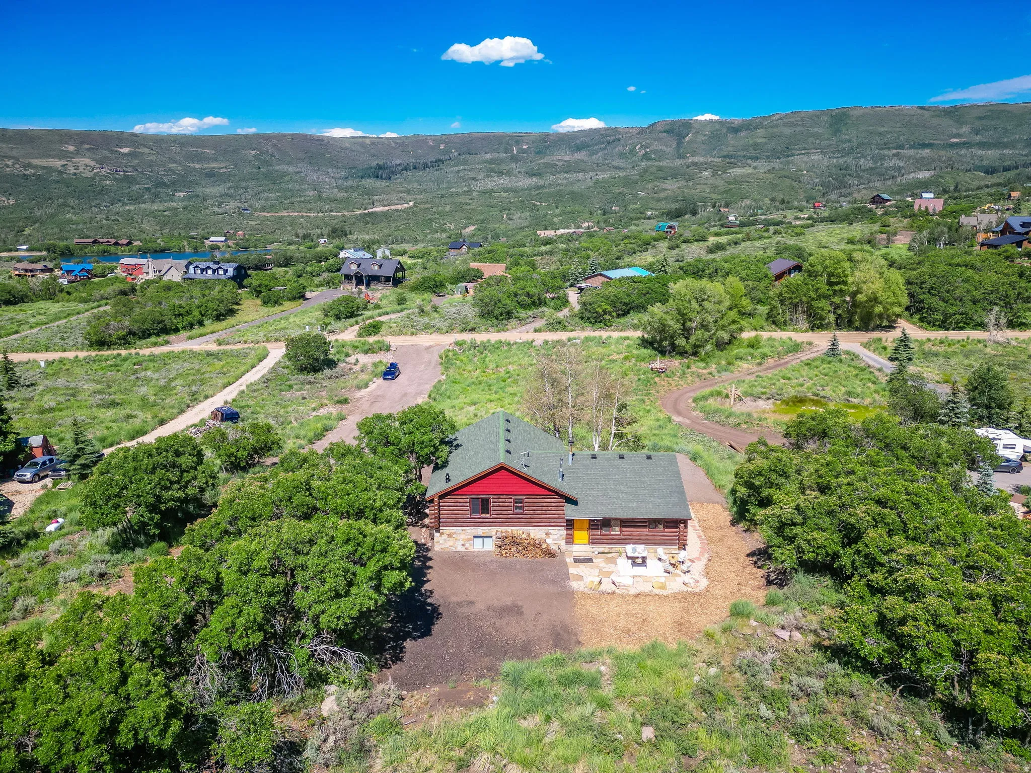 Log cabin style residence with a green roof, red siding, and stone foundation