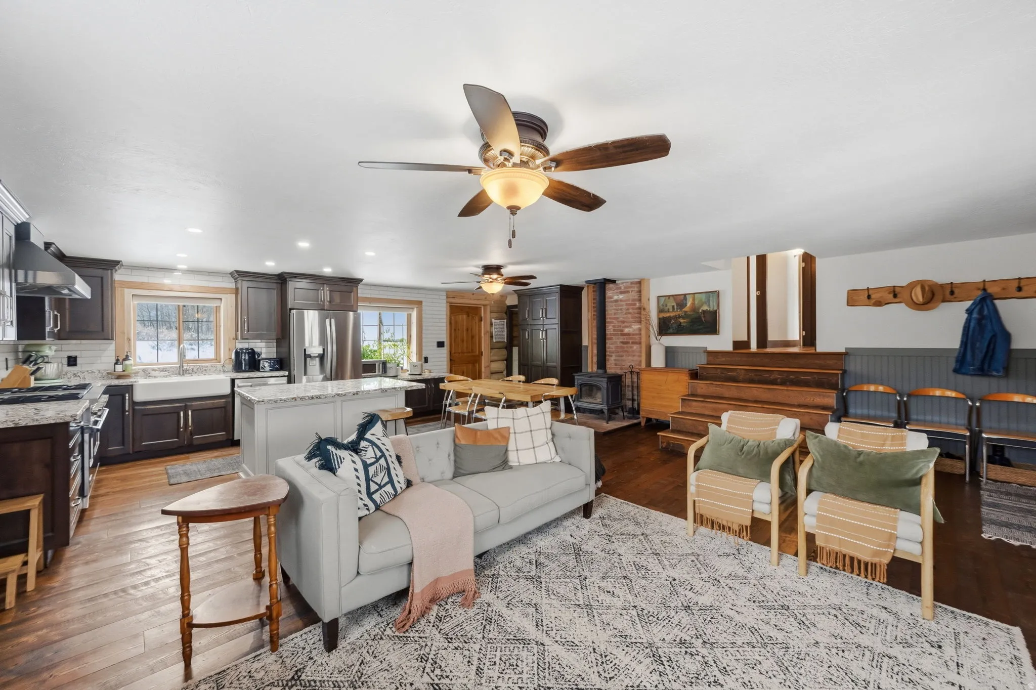 Living room with a wood stove, dark wood finished floors, recessed lighting, and a ceiling fan