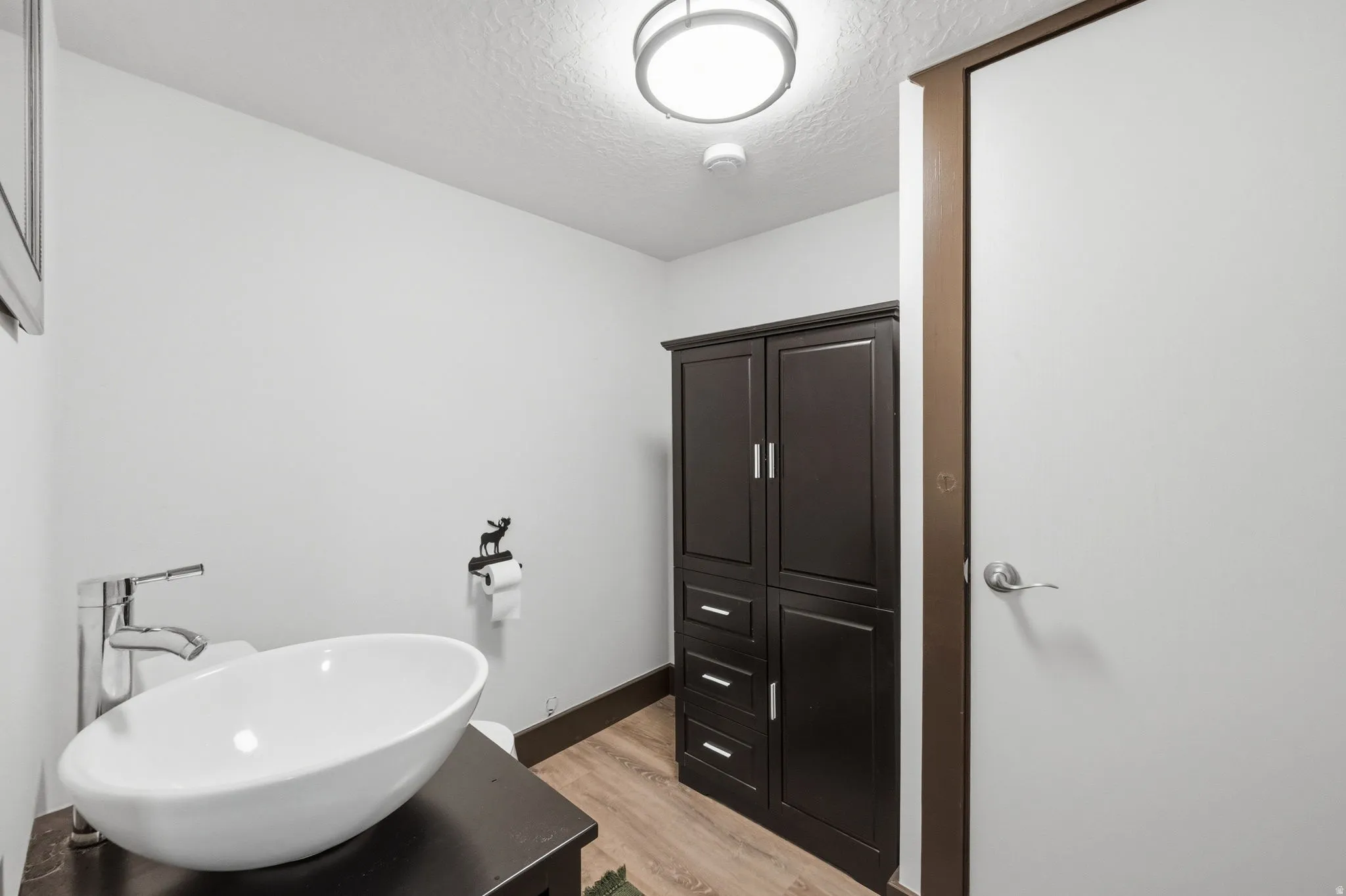 Bathroom featuring light wood finished floors, a textured ceiling, and vanity