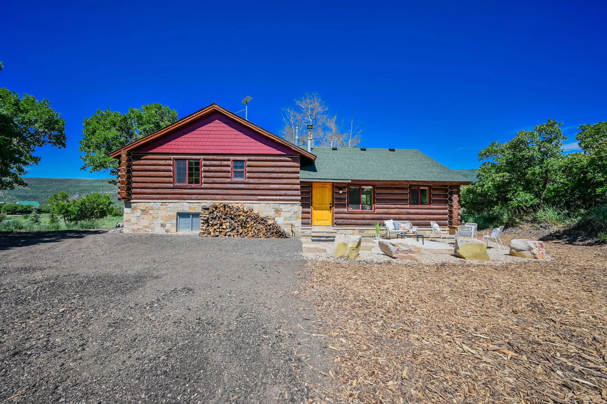 Log-sided dwelling featuring a stone foundation and a red gable accent