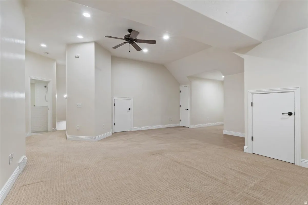 Bonus room with a ceiling fan, light colored carpet, and vaulted ceiling