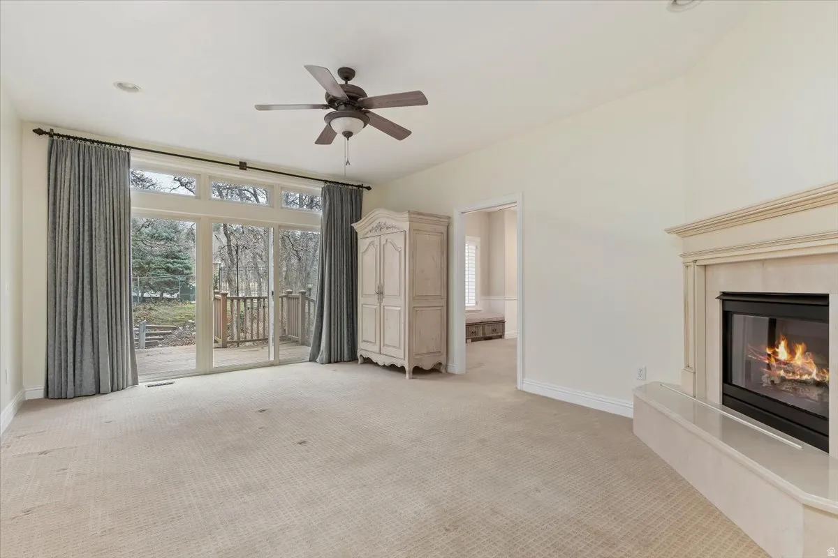 Unfurnished living room featuring a fireplace, a ceiling fan, and light colored carpet
