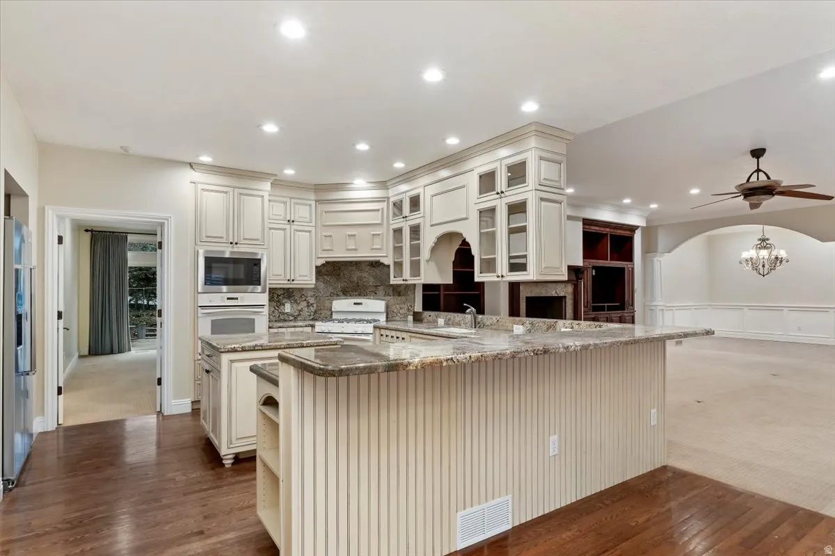 Kitchen featuring light stone countertops, a ceiling fan, glass insert cabinets, dark carpet, and recessed lighting