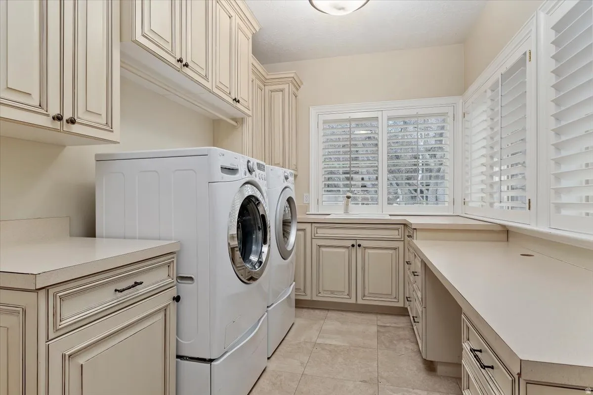 Laundry room with cabinet space, light tile patterned floors, and washer and clothes dryer