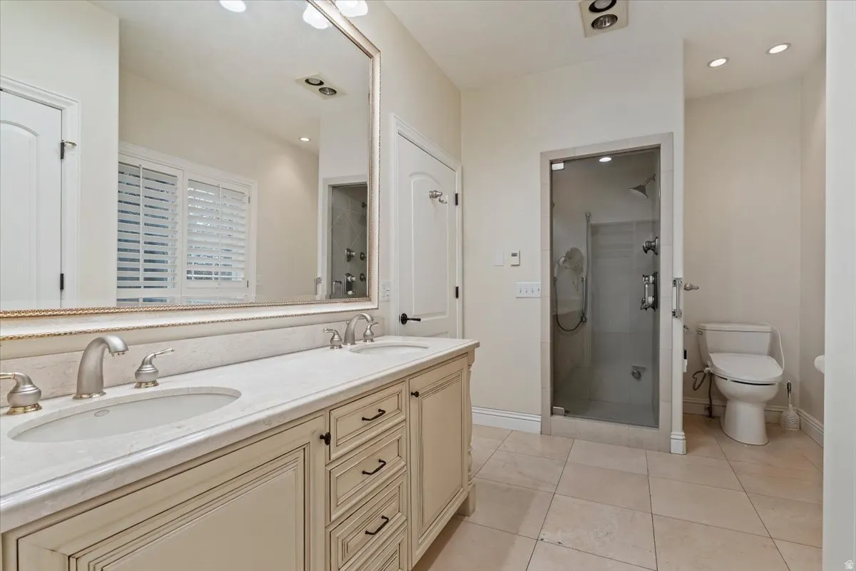 Full bath featuring double vanity, a stall shower, light tile patterned floors, and recessed lighting