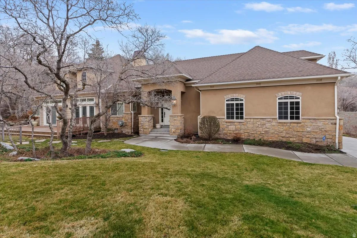 View of front of home featuring stucco siding, a front yard, and stone siding