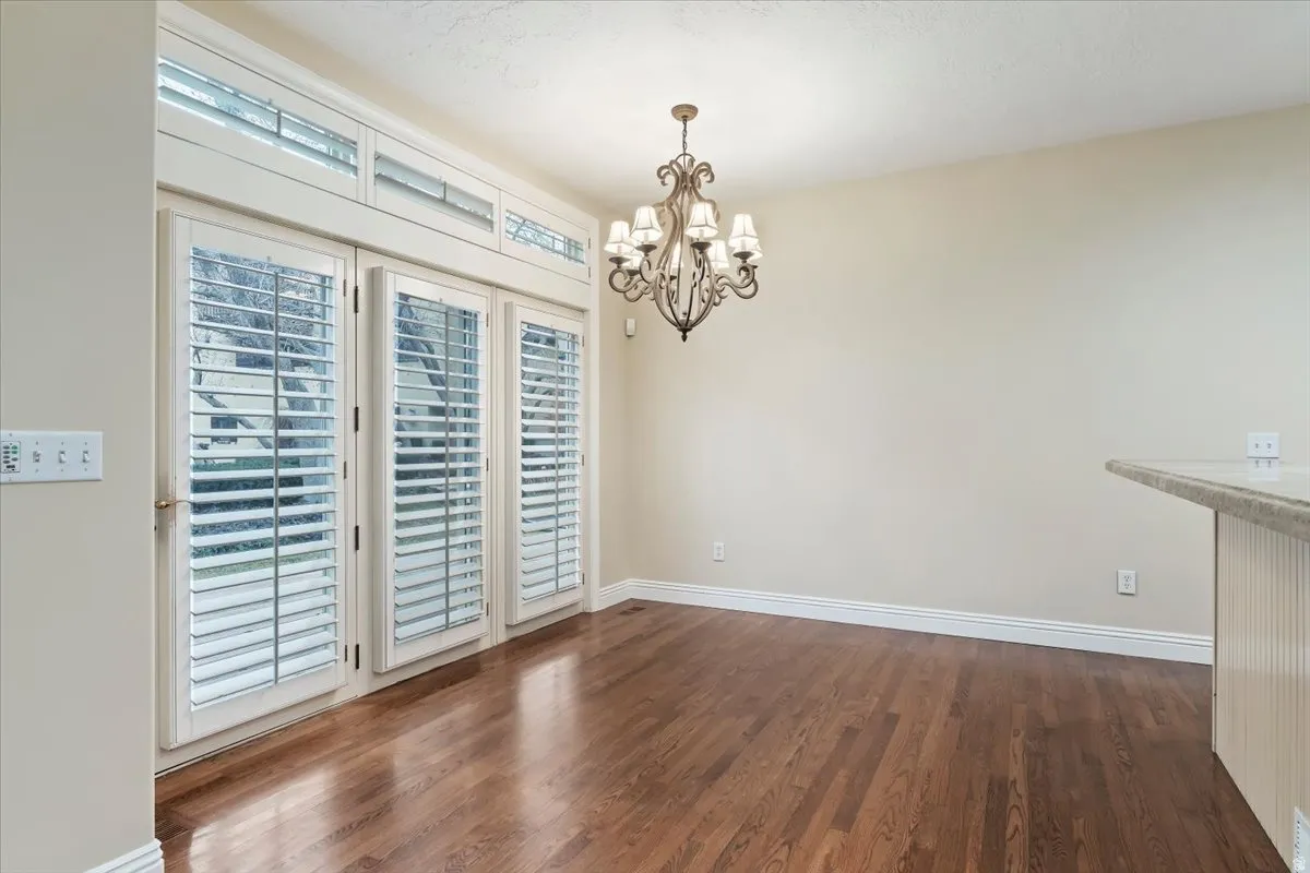 Unfurnished dining area featuring dark wood-style floors and a chandelier