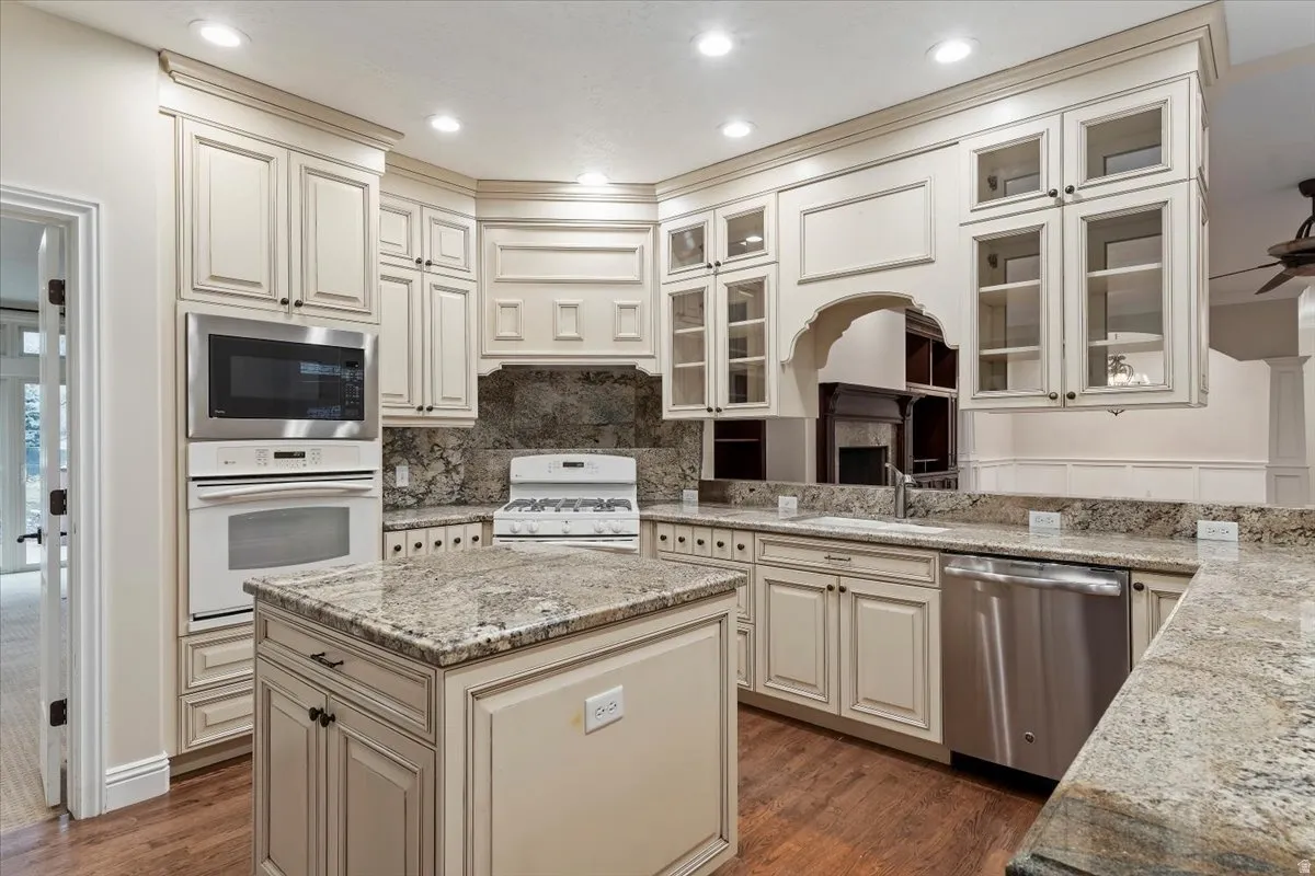Kitchen featuring light stone counters, a center island, stainless steel appliances, cream cabinetry, and tasteful backsplash