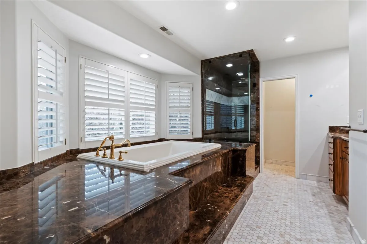 Bathroom featuring vanity, a shower stall, a bath, light tile patterned floors, and recessed lighting