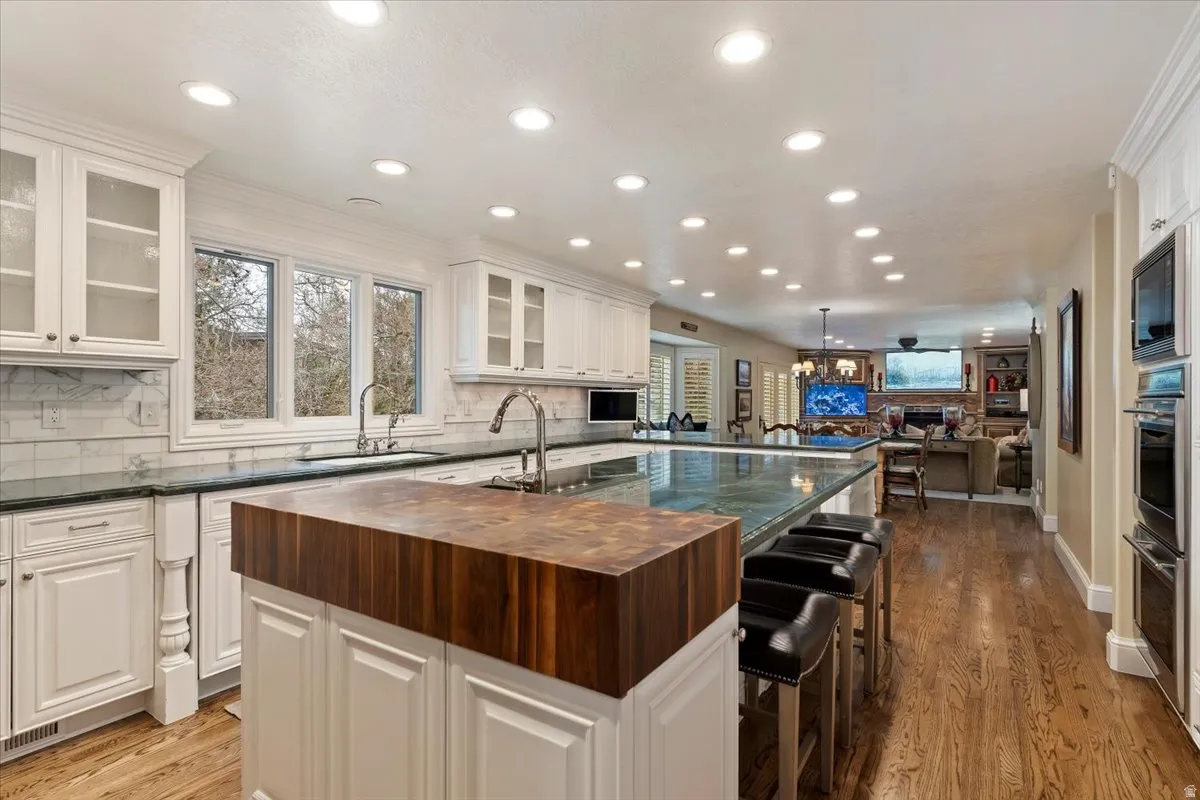 Kitchen with backsplash, a kitchen breakfast bar, open floor plan, and white cabinetry