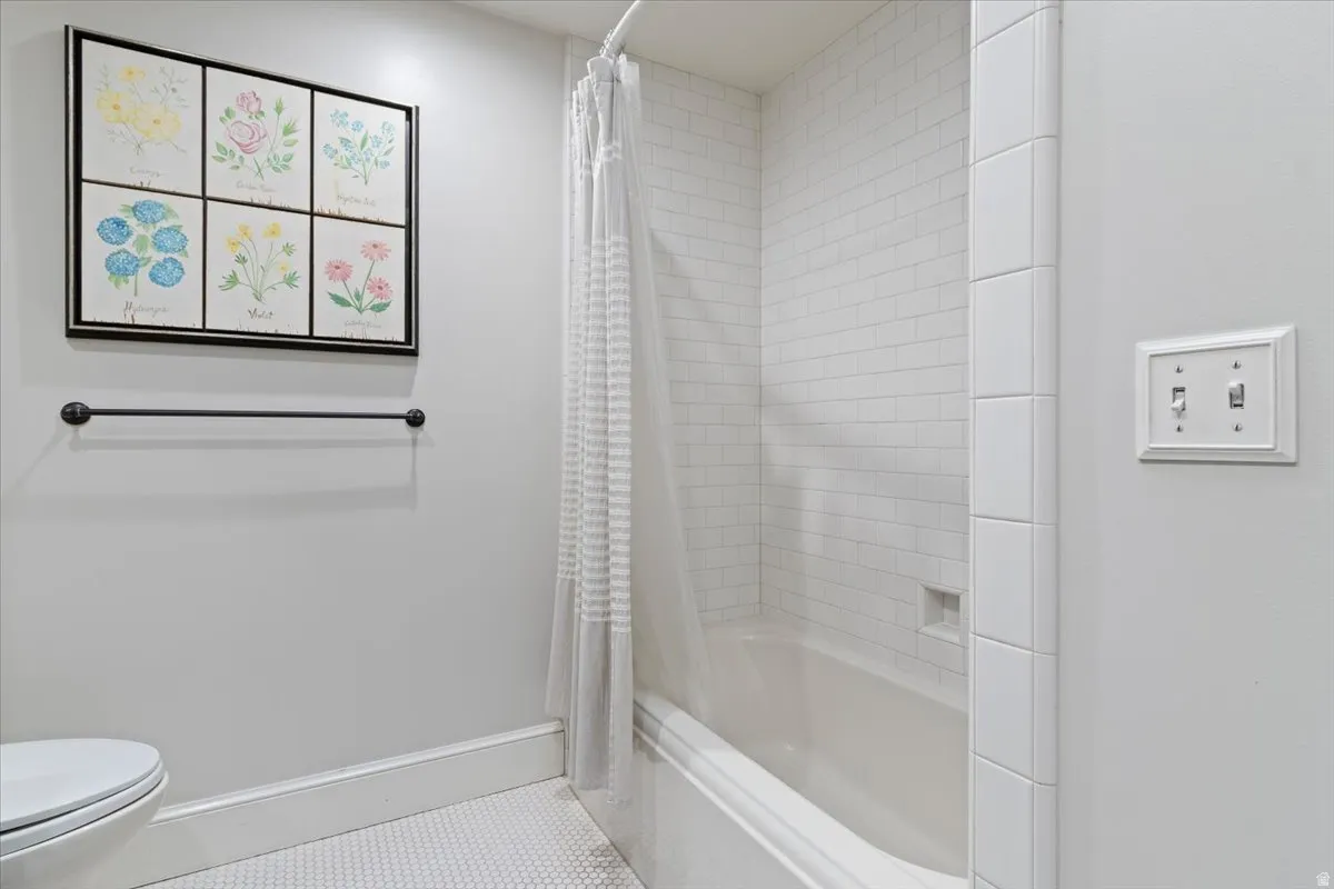 Full bathroom featuring shower / bath combination with curtain and light tile patterned floors