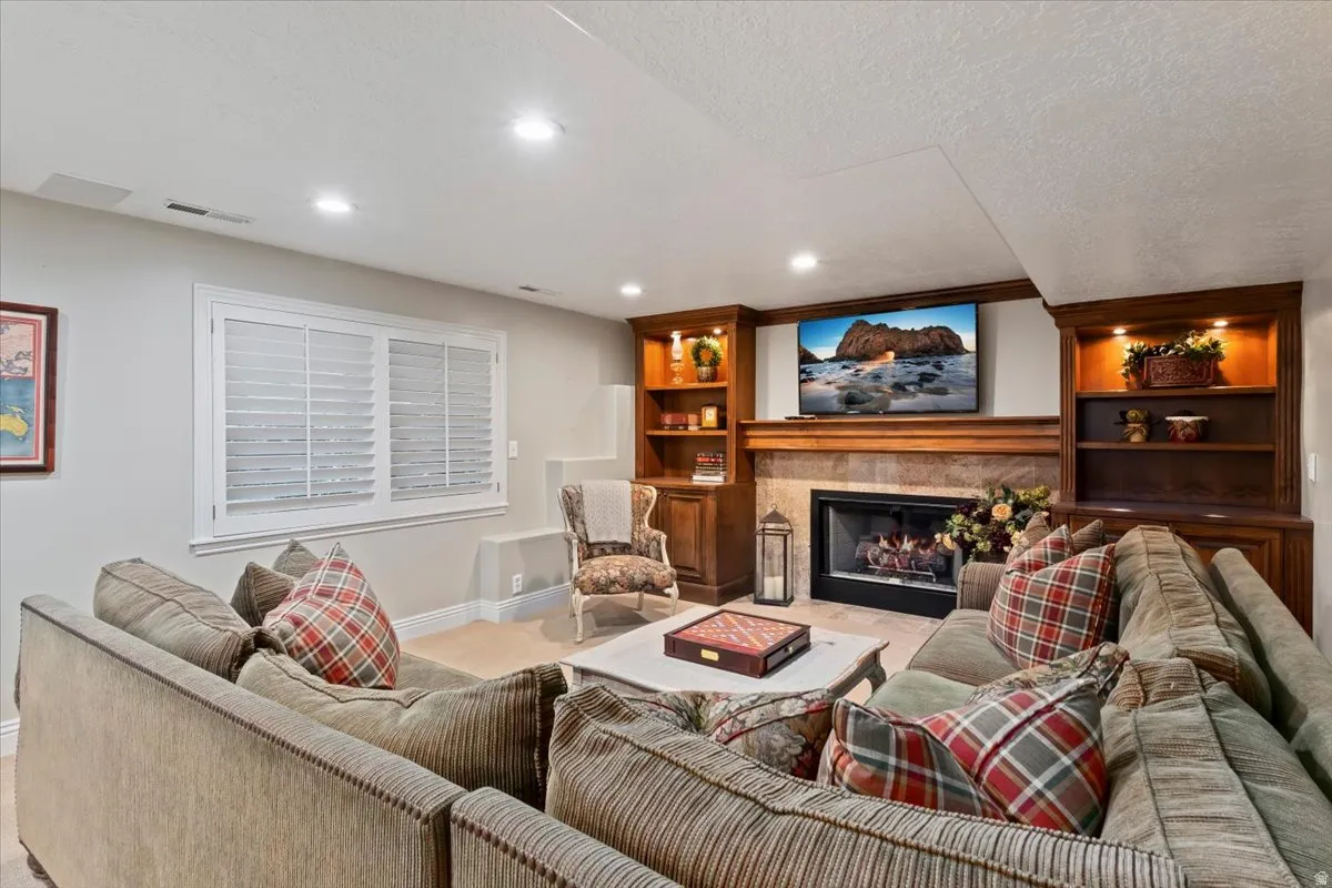 Living room with built in features, a tile fireplace, a textured ceiling, recessed lighting, and light carpet