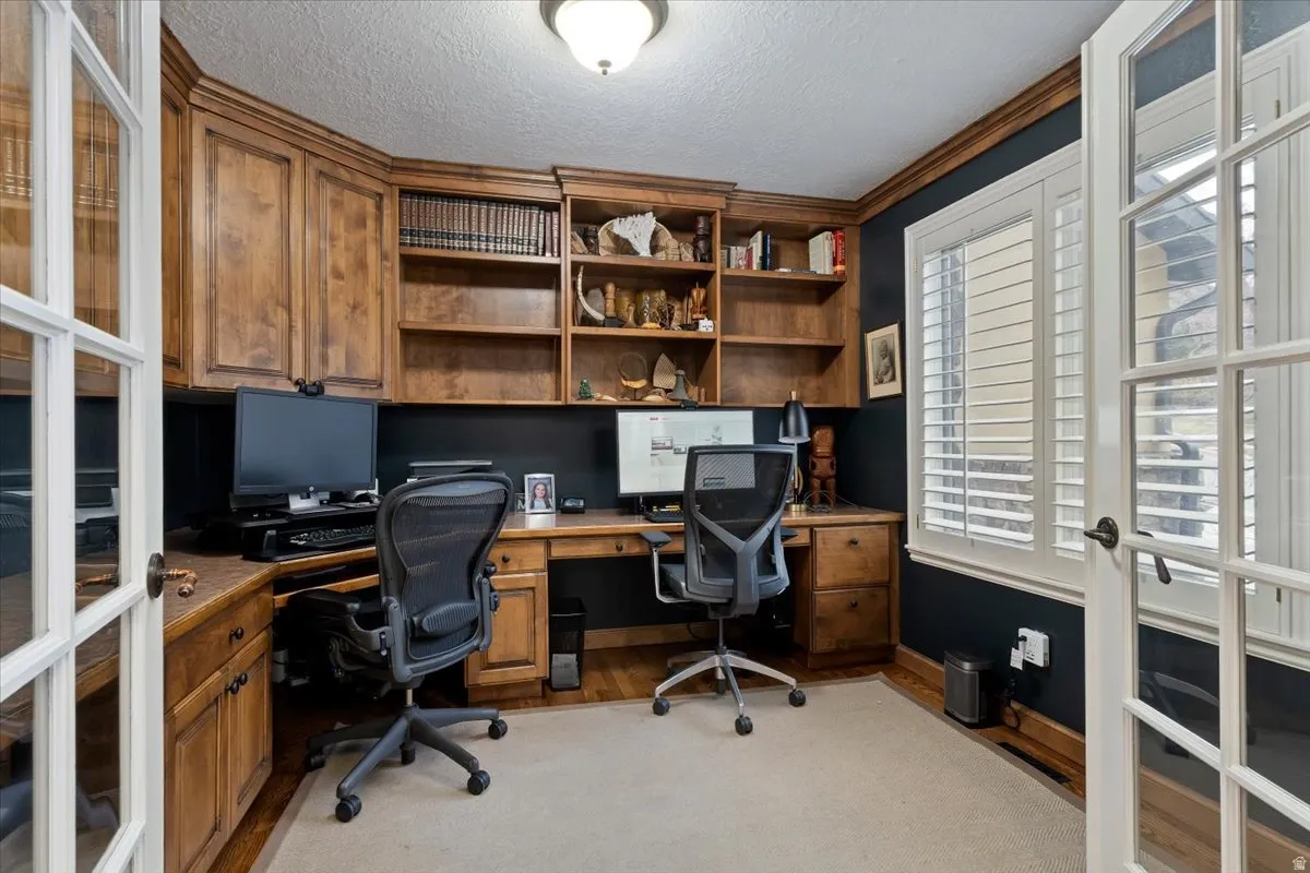 Home office with french doors, light wood finished floors, a textured ceiling, and crown molding