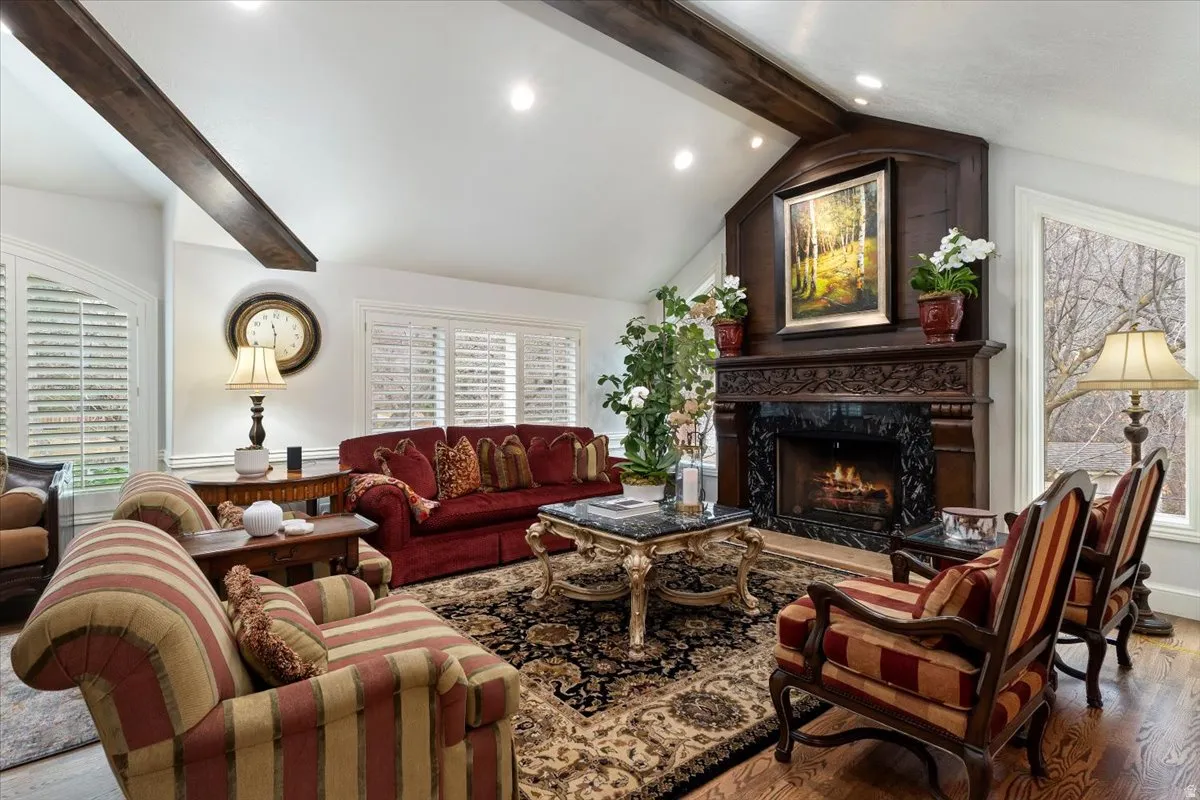 Living area featuring beam ceiling, wood finished floors, a fireplace, and recessed lighting