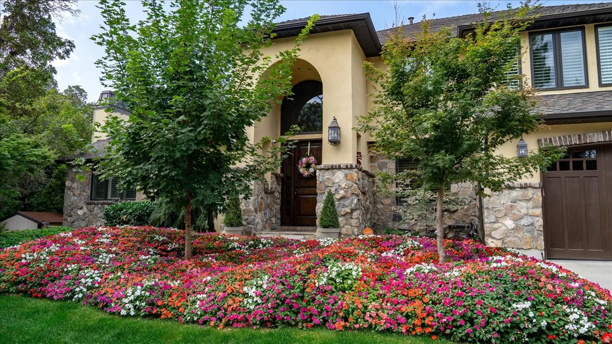 Entrance to property with stone siding, an attached garage, and stucco siding