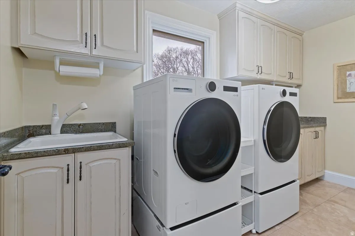 Laundry area with cabinet space, light tile patterned floors, and washing machine and clothes dryer