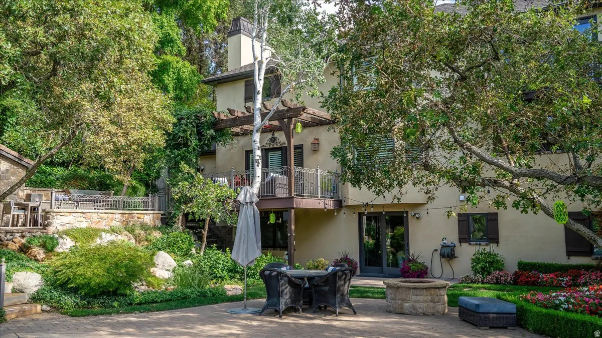 Rear view of property with a balcony, stucco siding, french doors, a patio, and a chimney