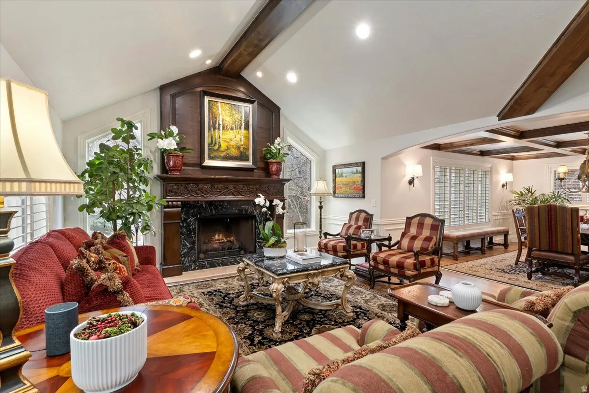 Living room with beam ceiling, a premium fireplace, wainscoting, a decorative wall, and recessed lighting