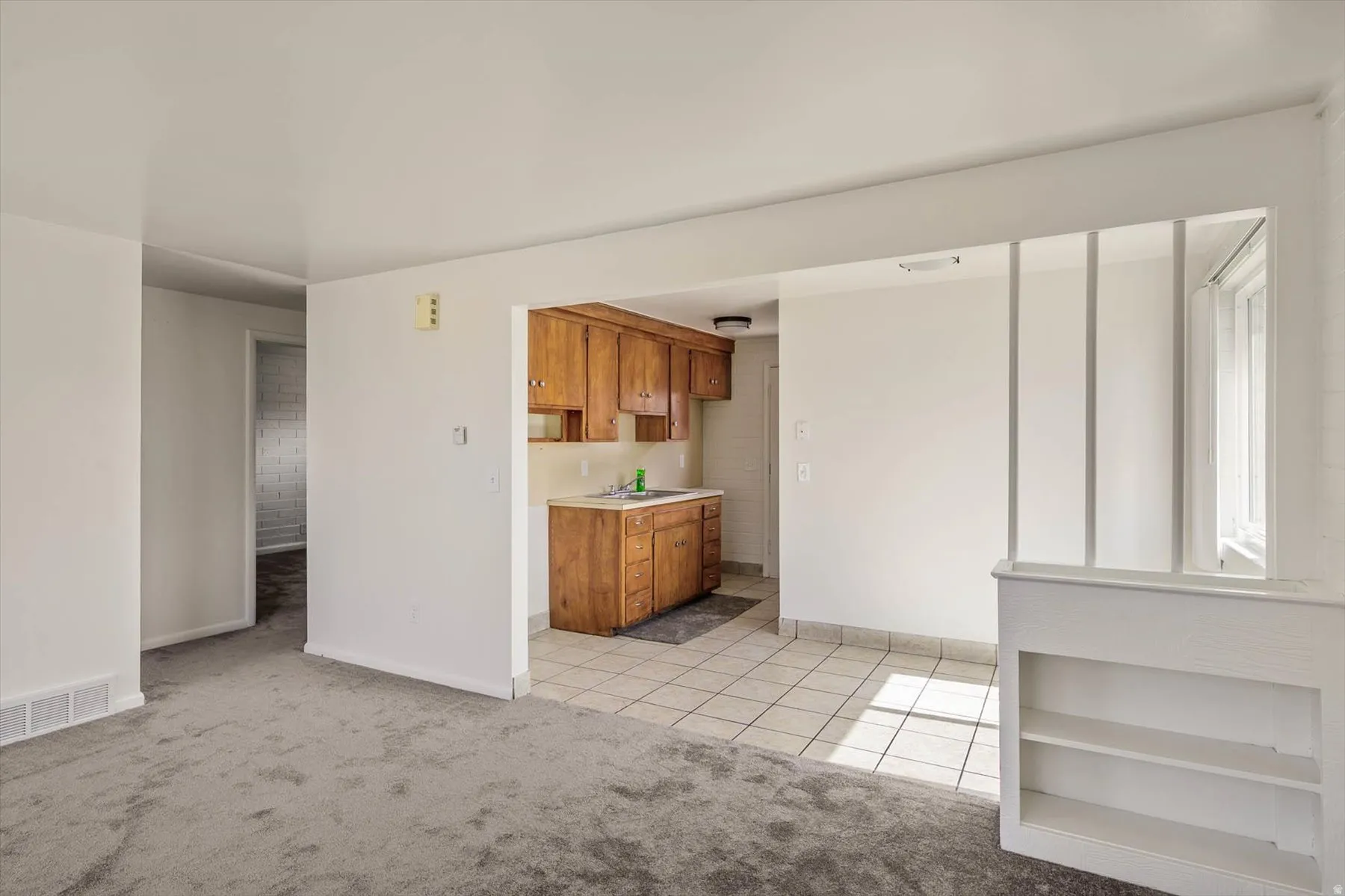 Unfurnished living room featuring light tile patterned floors and light carpet