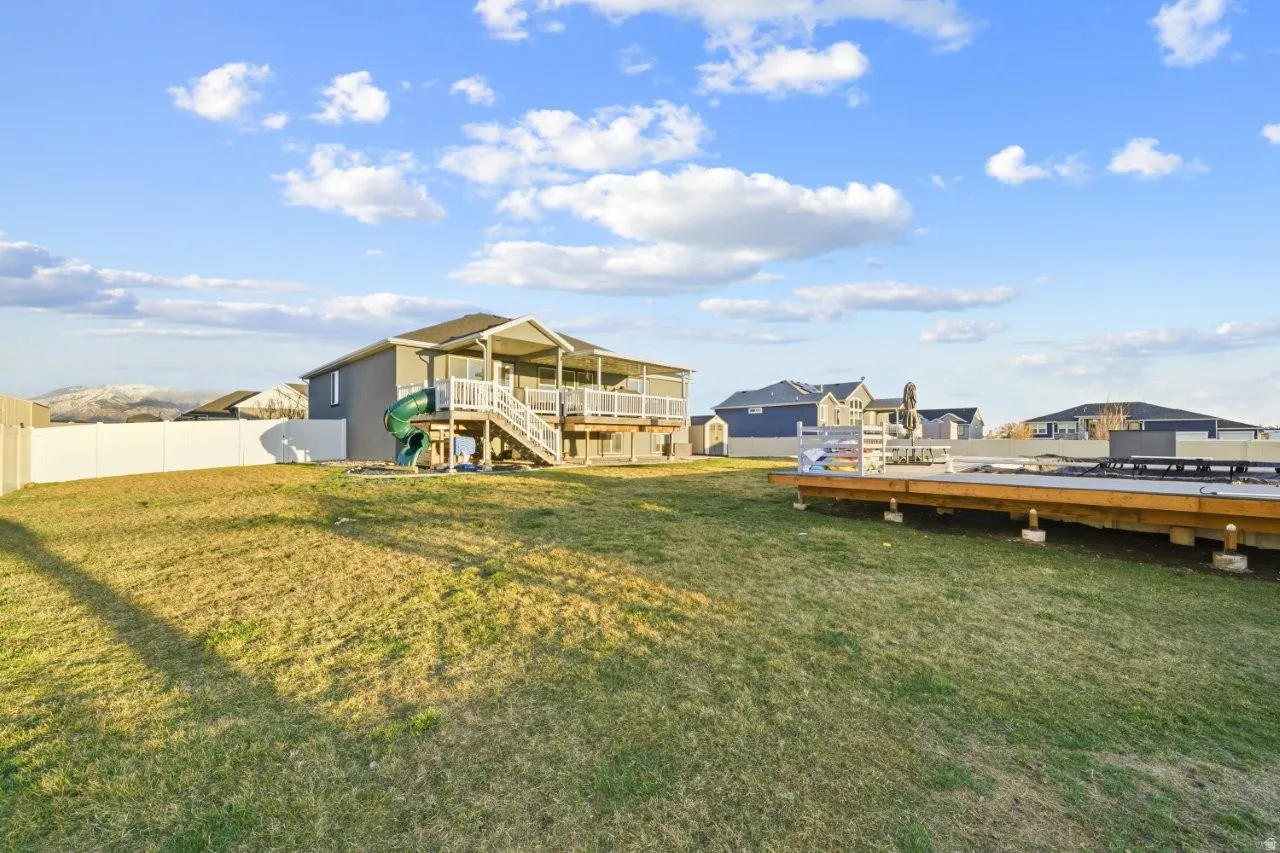 View of green lawn with a deck and a residential view