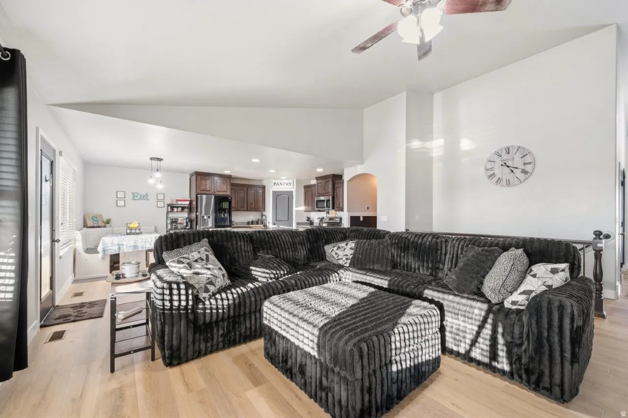 Living area featuring a ceiling fan, light wood-type flooring, arched walkways, vaulted ceiling, and recessed lighting