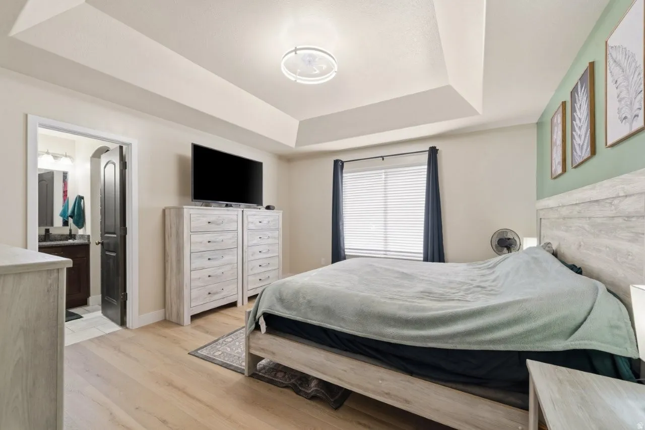 Bedroom with a tray ceiling and light wood-style flooring